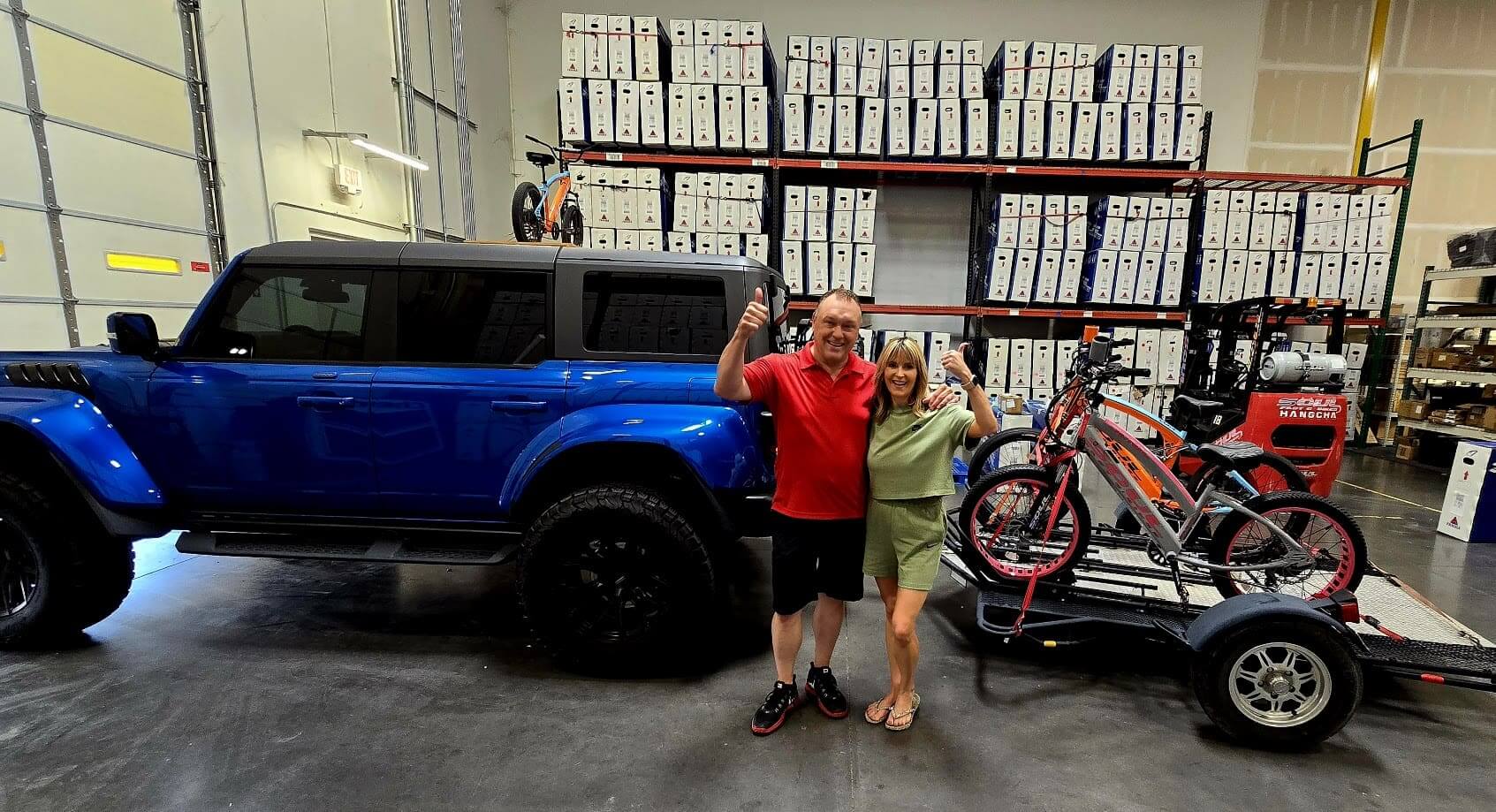 Couple celebrating with blue SUV and bikes.