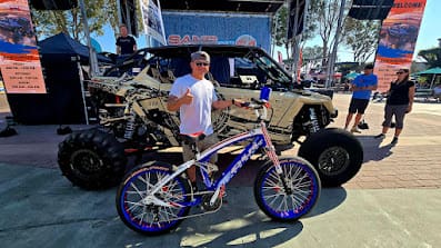 Man with bicycle in front of off-road vehicle.