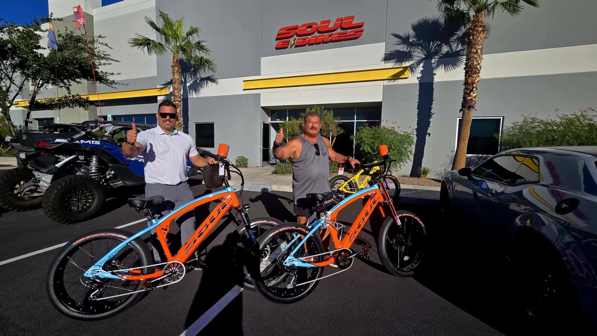 Two people with electric bikes, thumbs up.