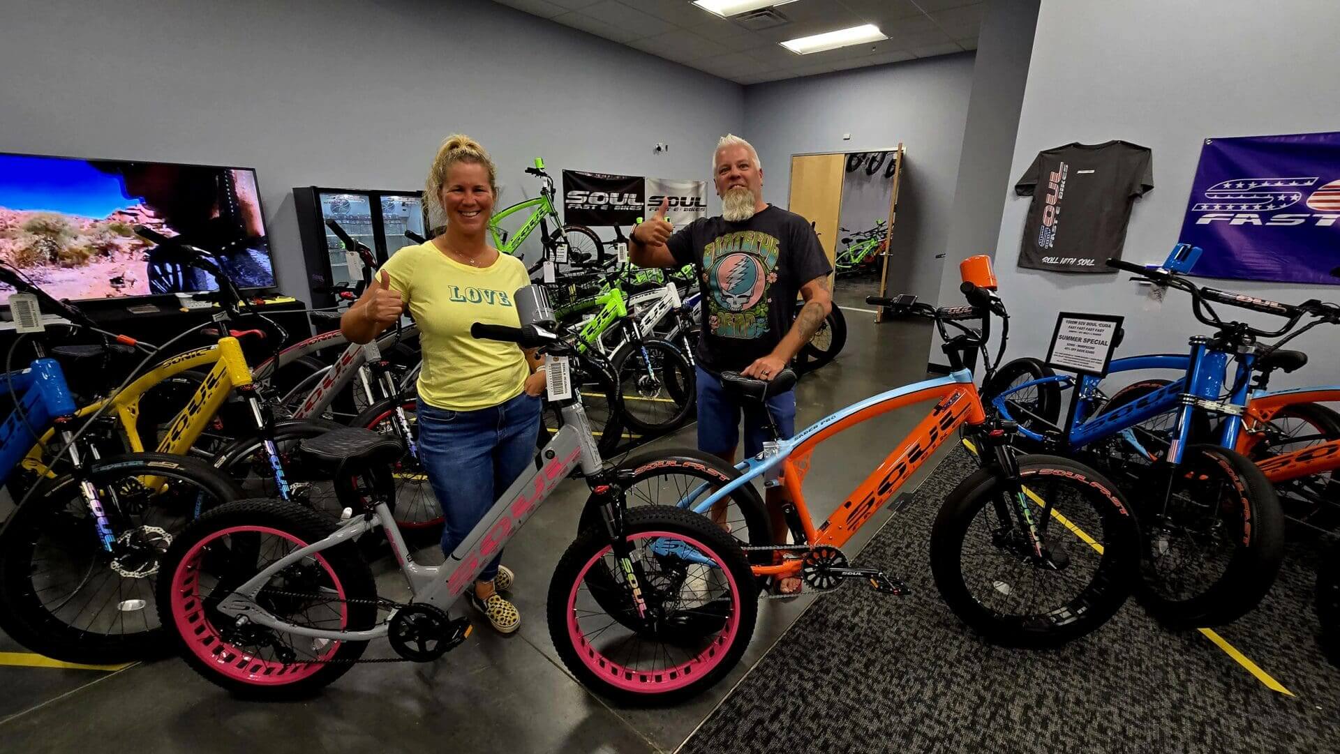 People posing with colorful bicycles in store.