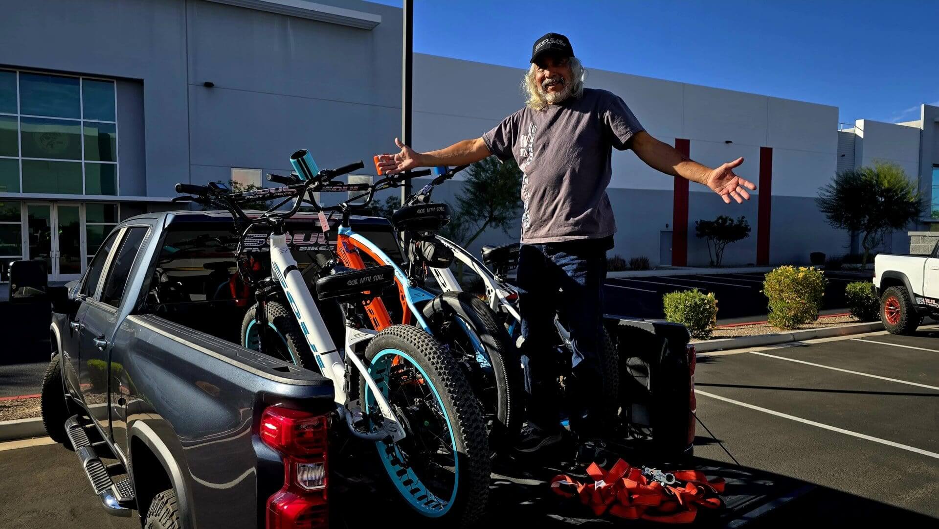 Man with bicycles loaded on truck bed.