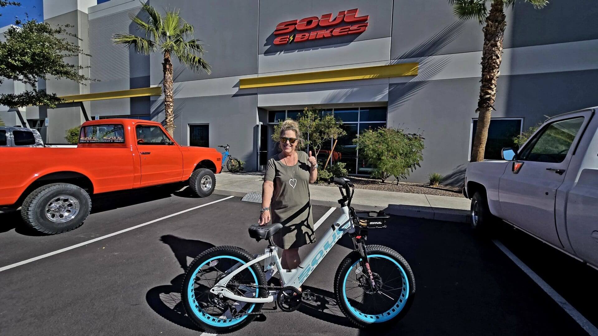 Person posing with electric bike outside store.