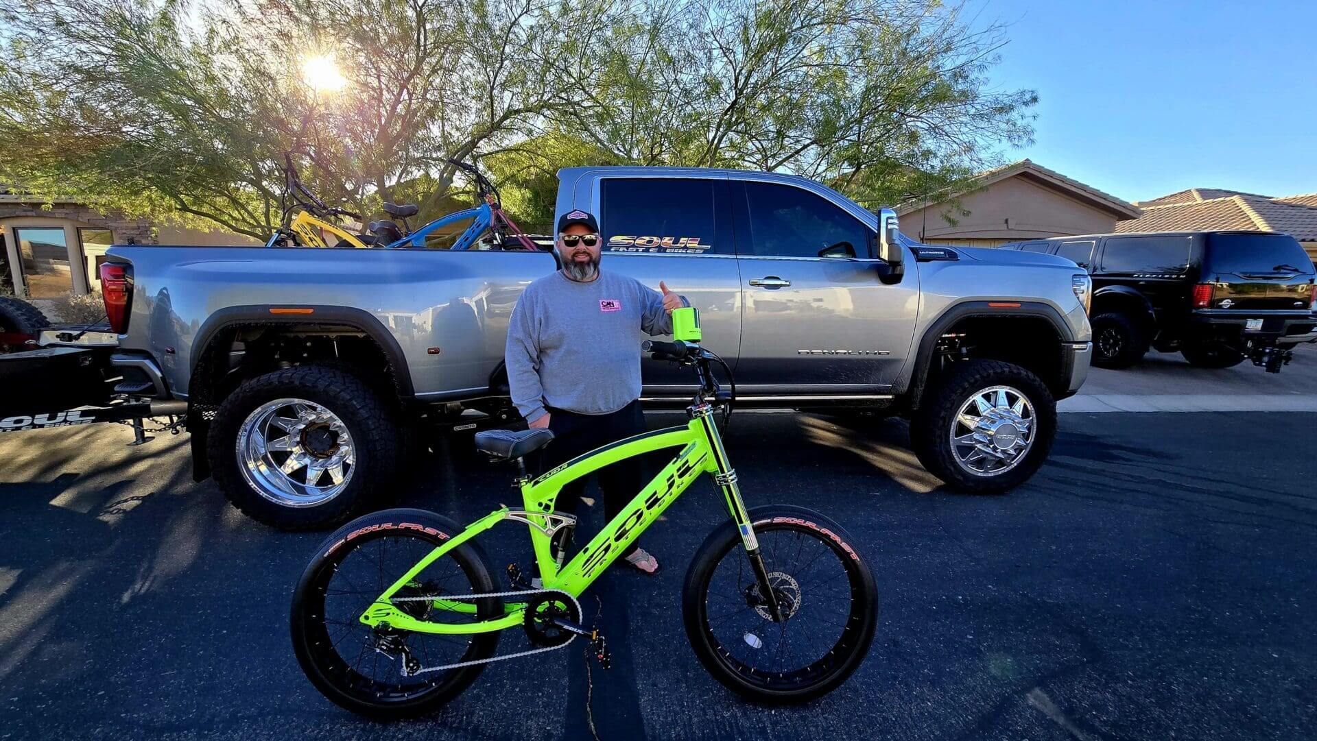 Man posing with green bike and truck.