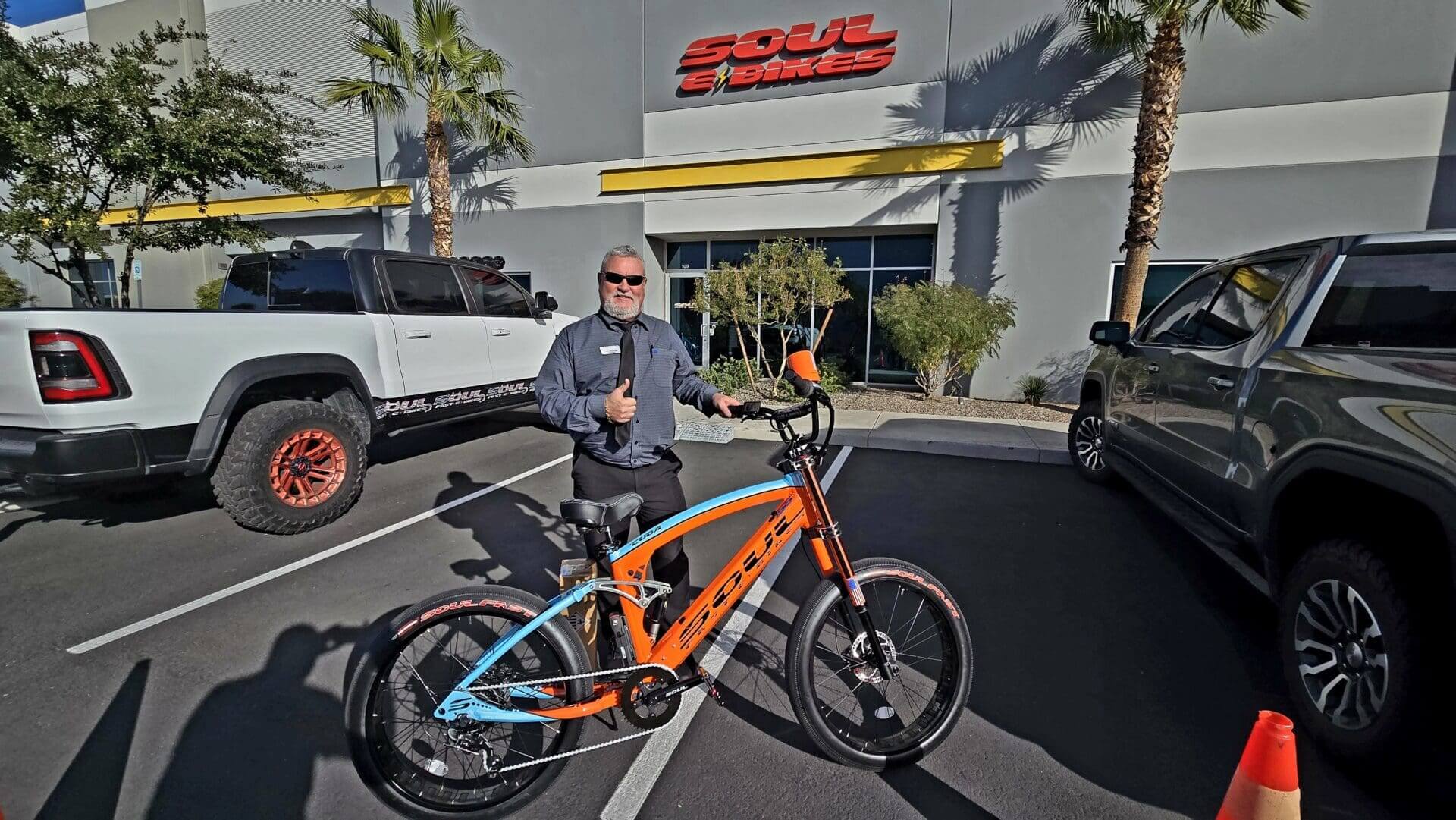 Man standing with an orange electric bike.