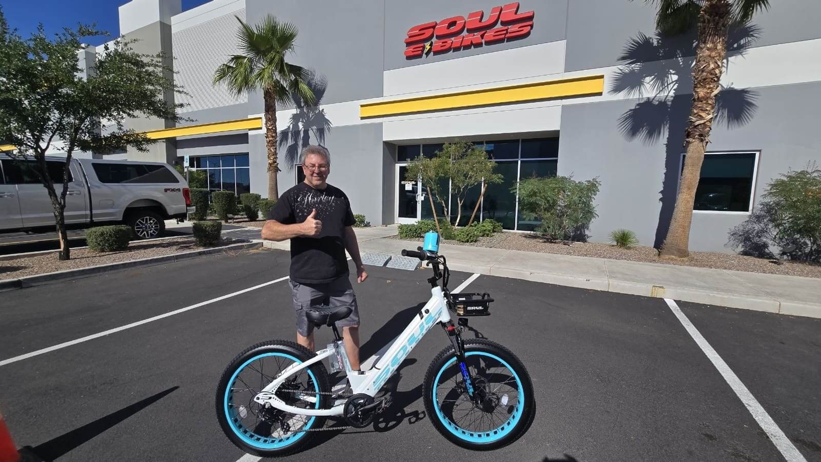 Man posing with bicycle outside a store.