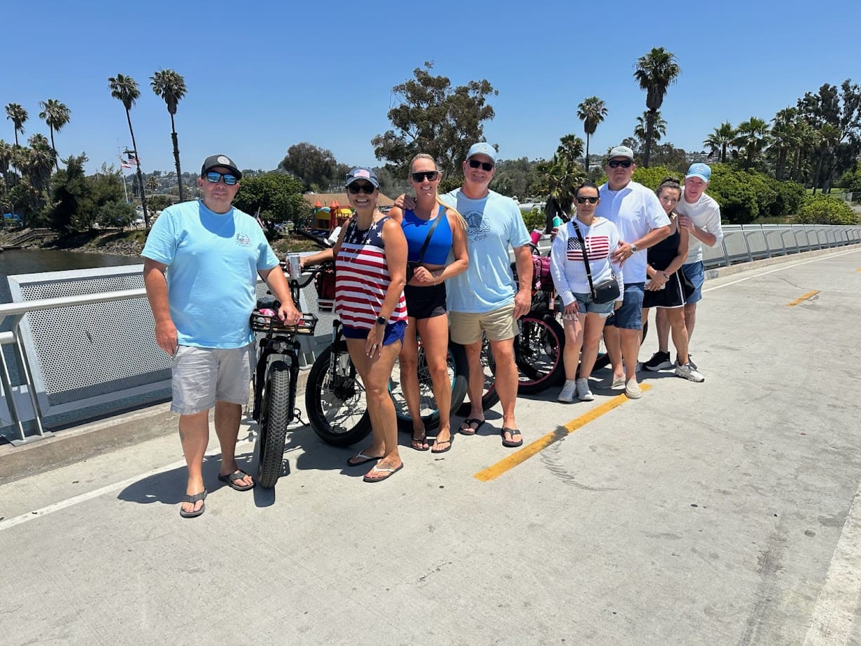 Group of people standing with bicycles outdoors.