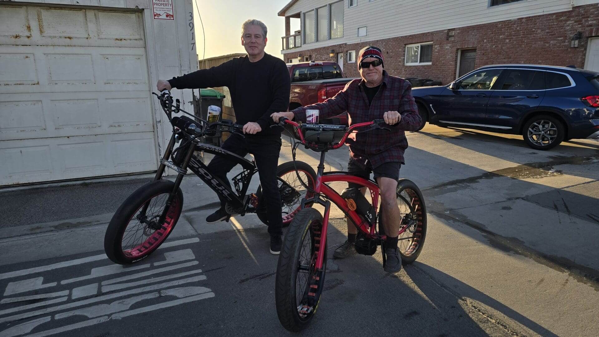 Two people on bicycles in a driveway.
