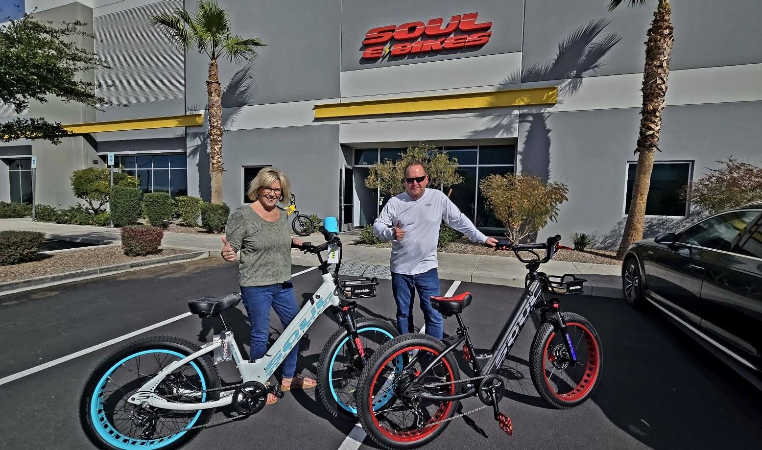 Two people with electric bikes outside building.