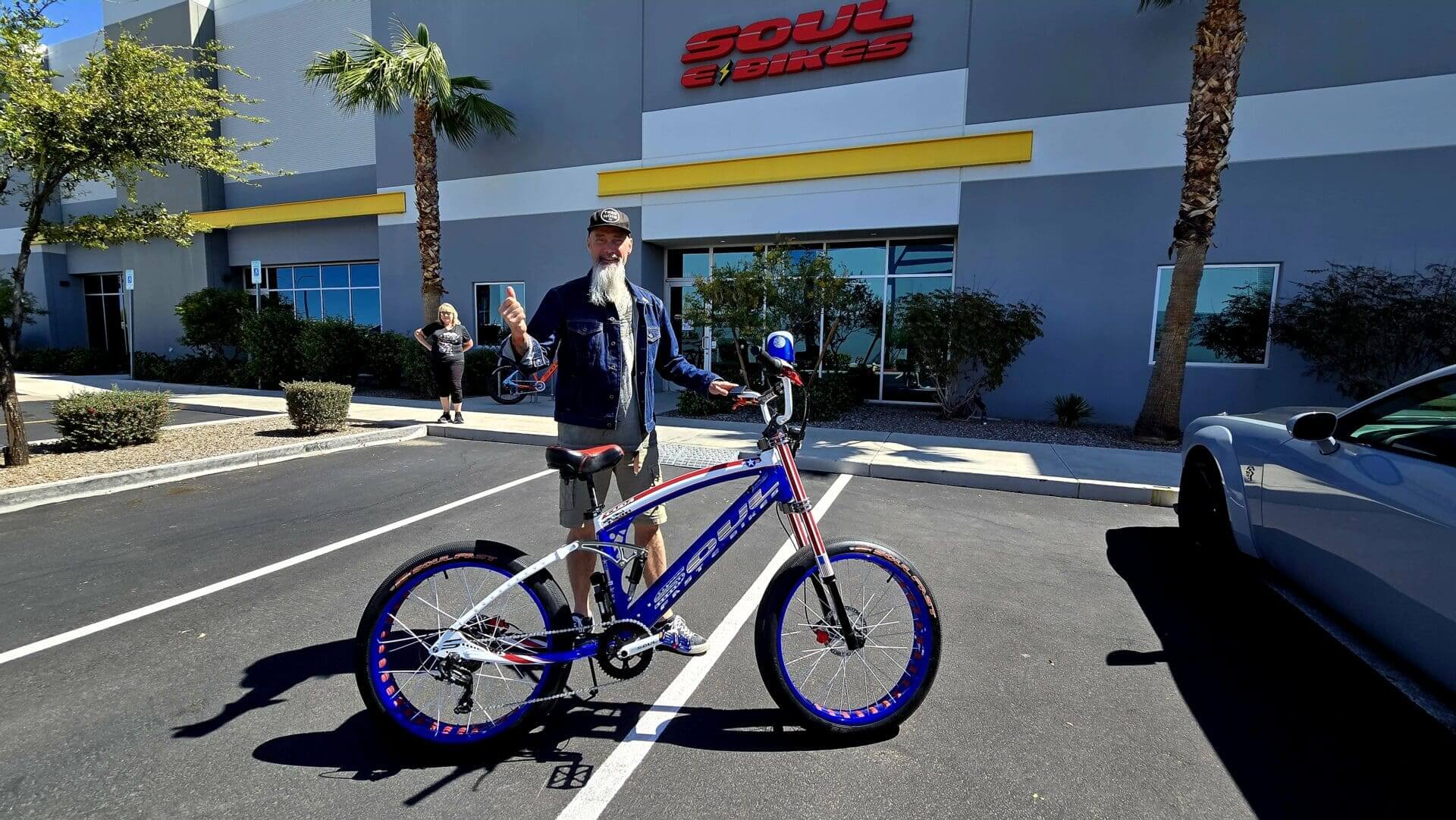 Man posing with a blue and white bicycle.