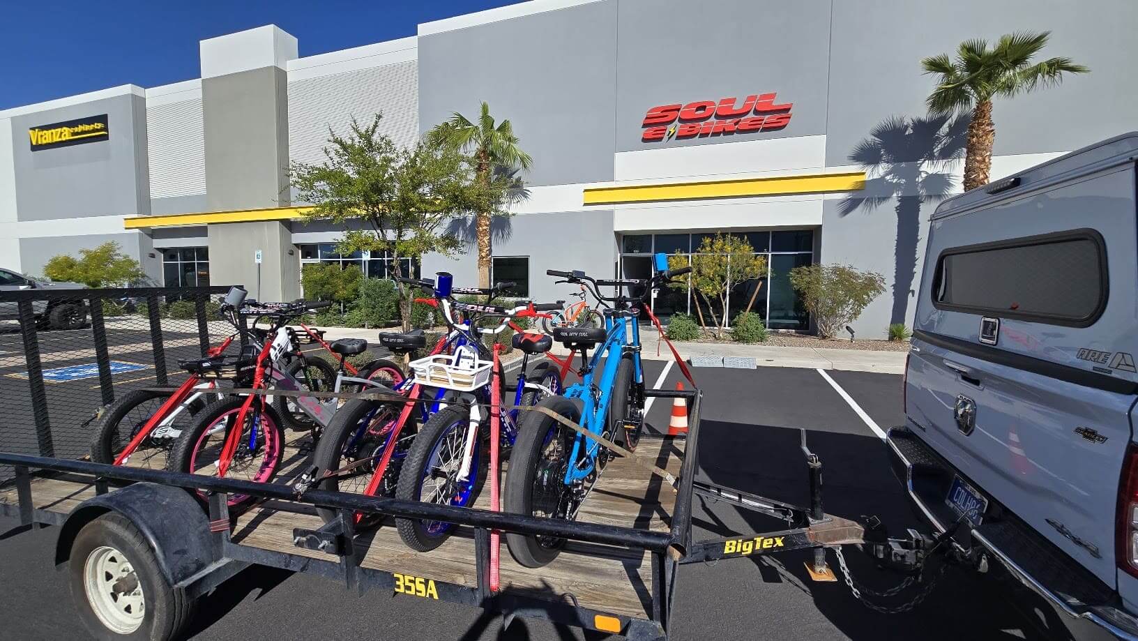 Trailer carrying colorful bikes outside shop.