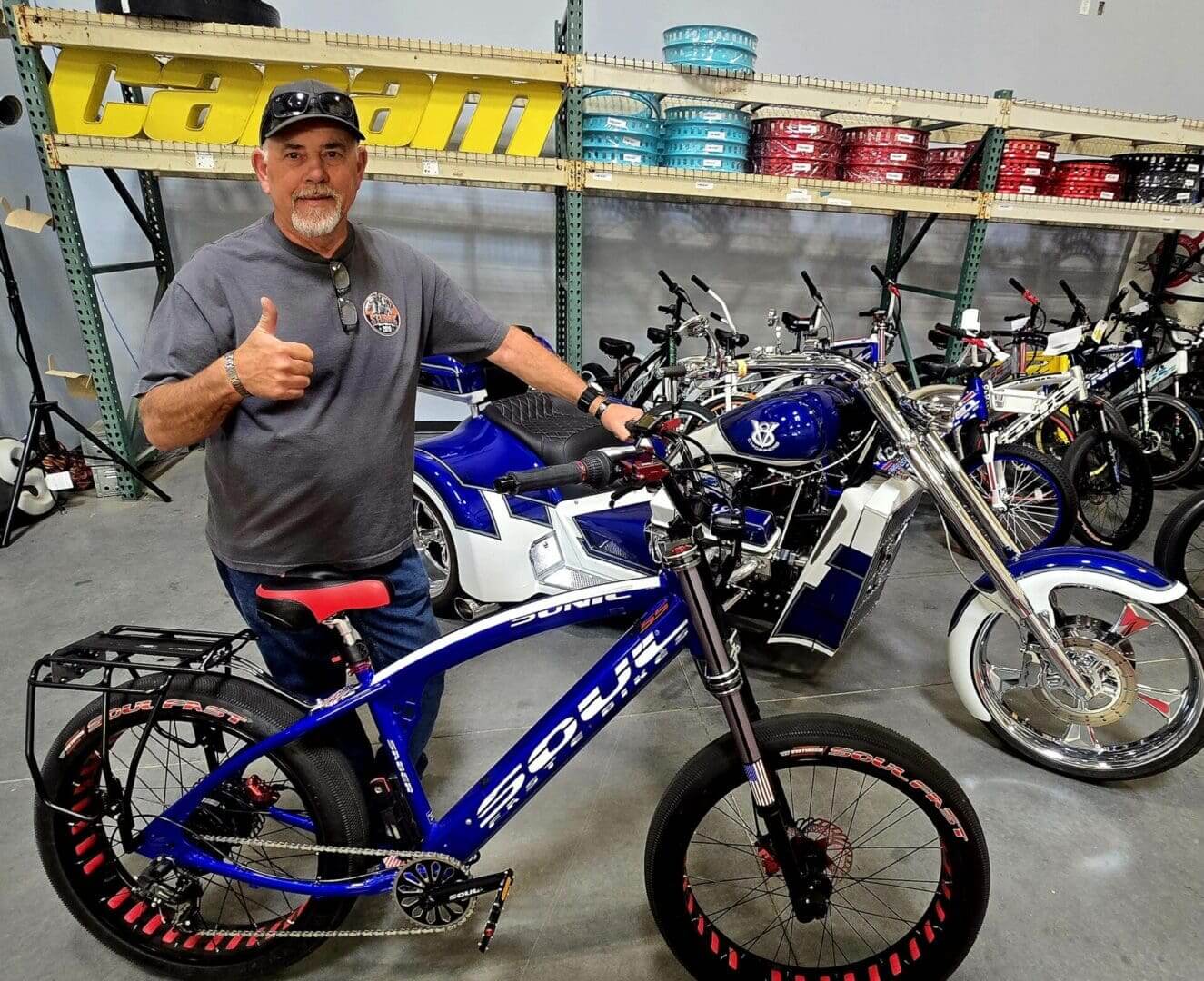 Man giving thumbs up beside blue bike.