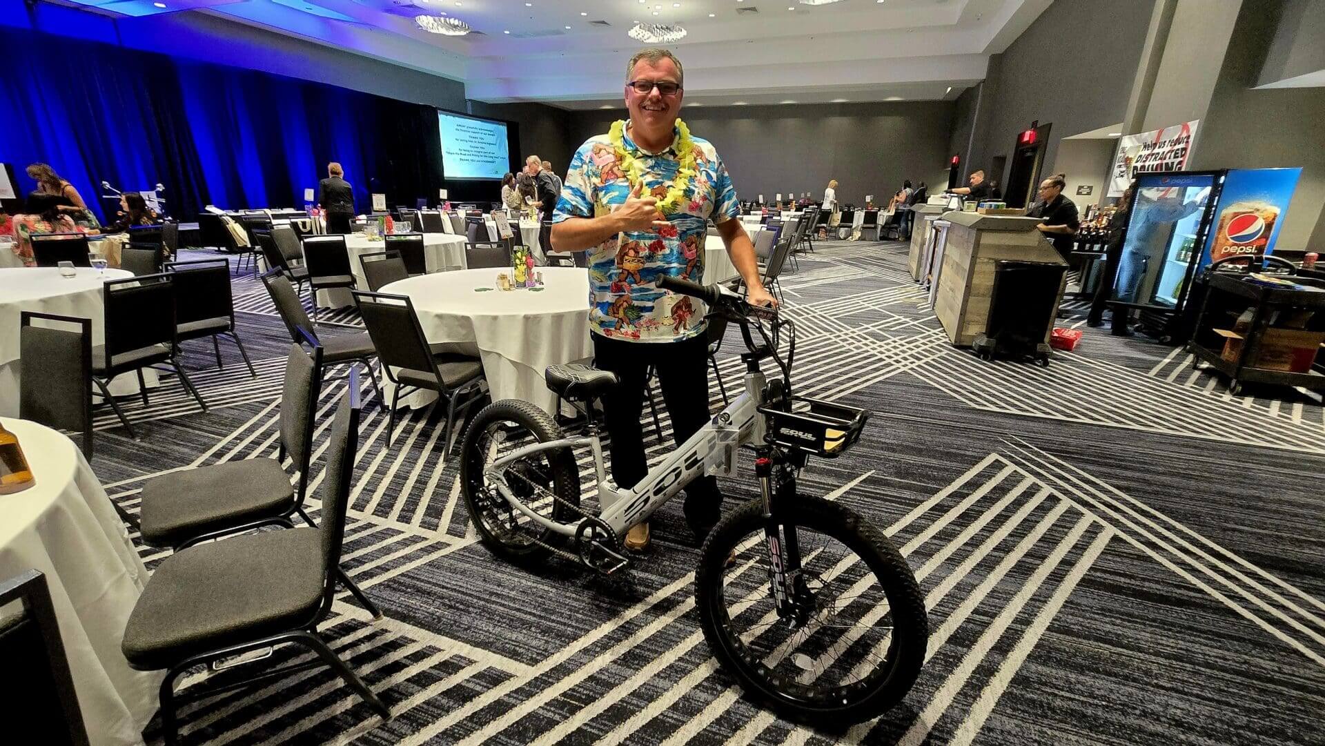 Man in colorful shirt with electric bike.