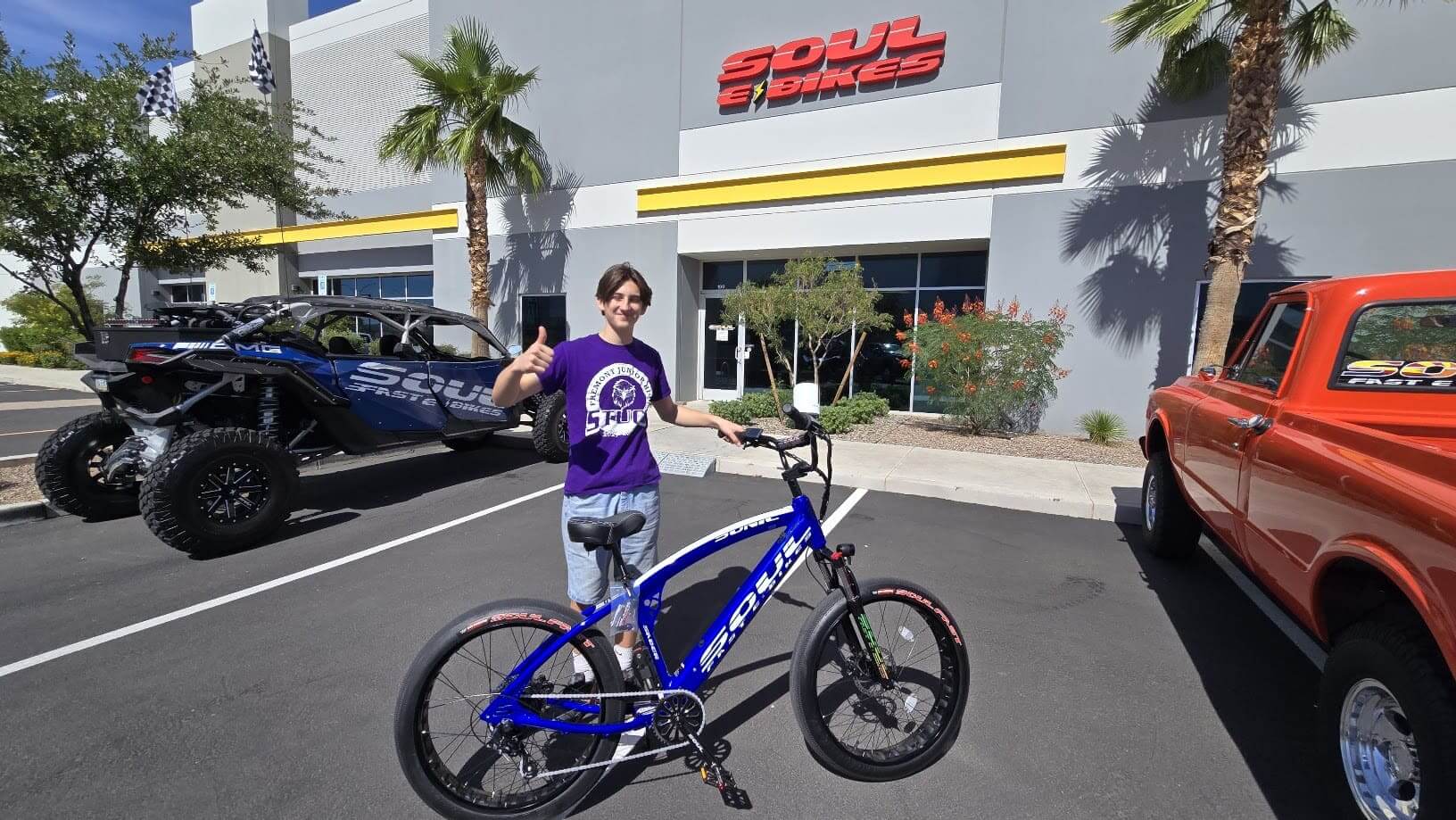 Man posing with blue bicycle outside store.