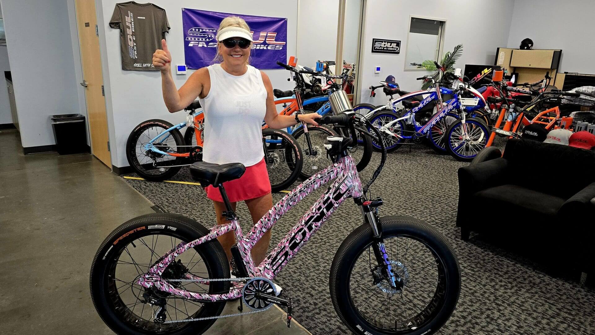 Woman posing with a pink electric bike.