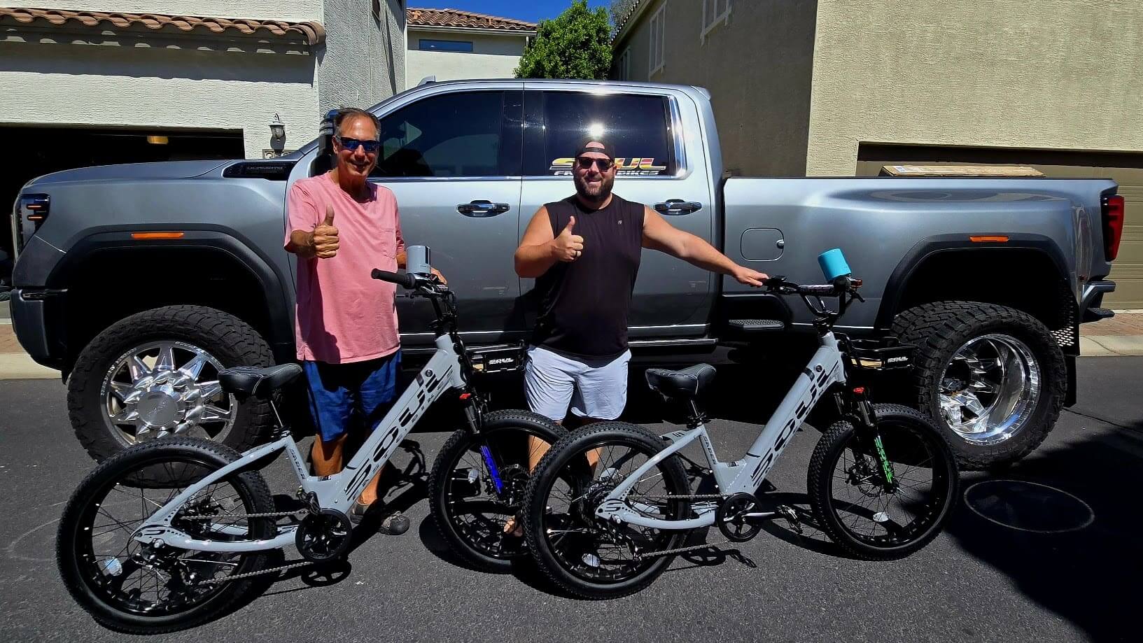 Two men with bikes in front of truck.