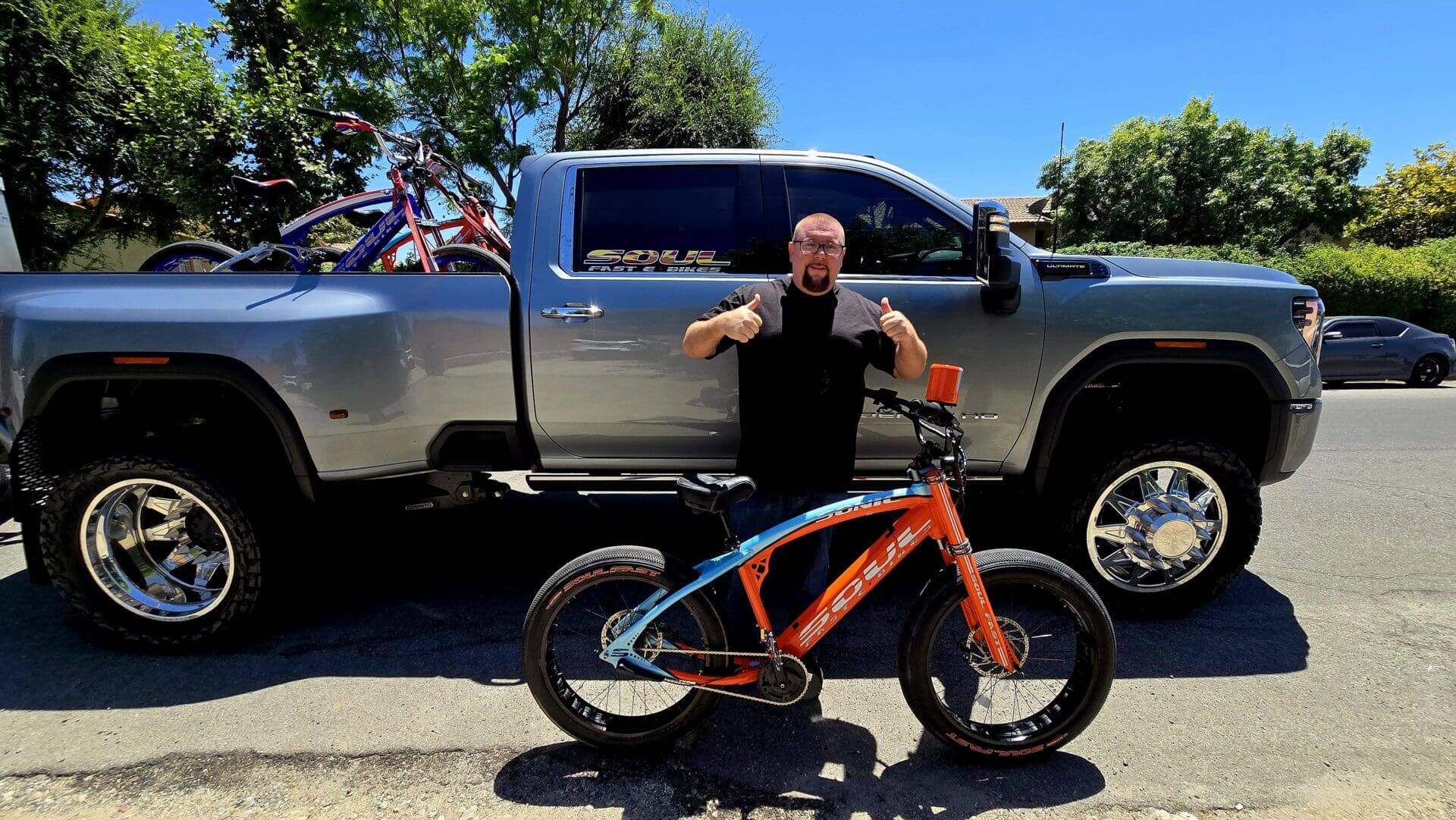 Man with bicycle in front of truck.