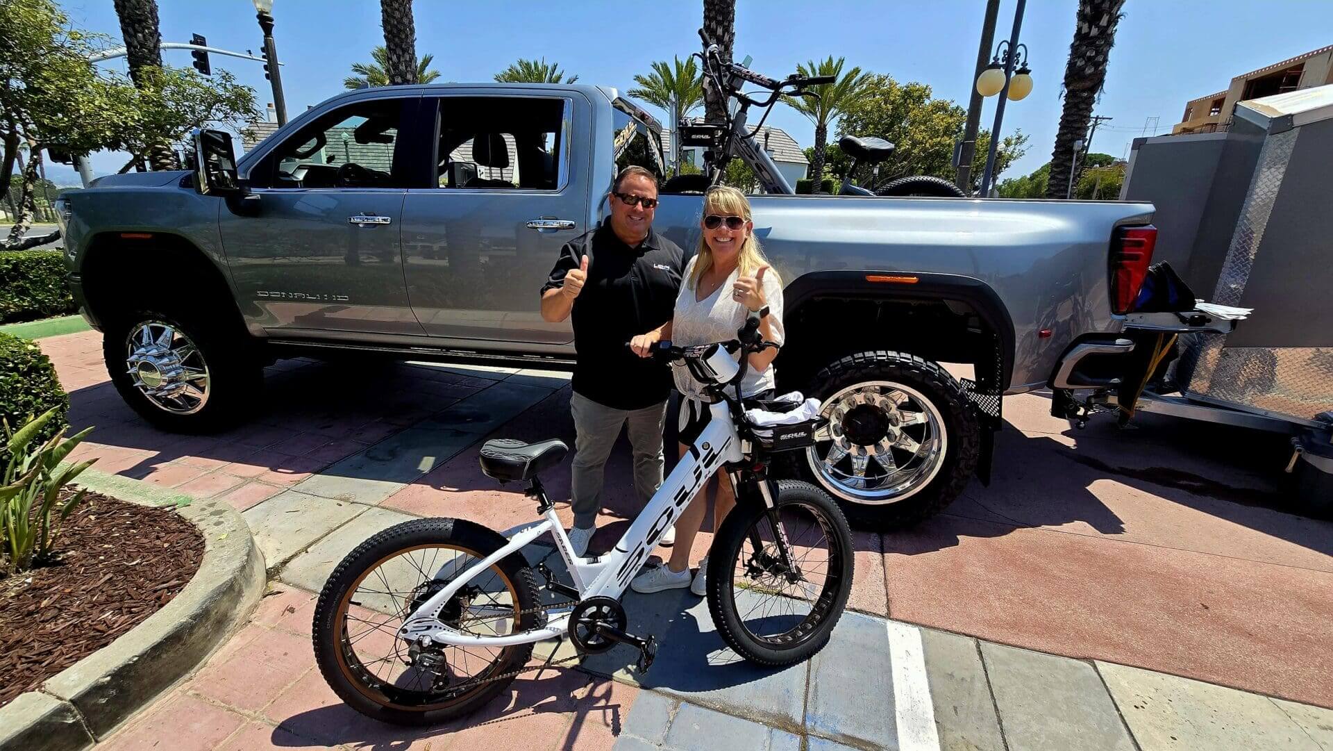Couple with bike in front of truck.