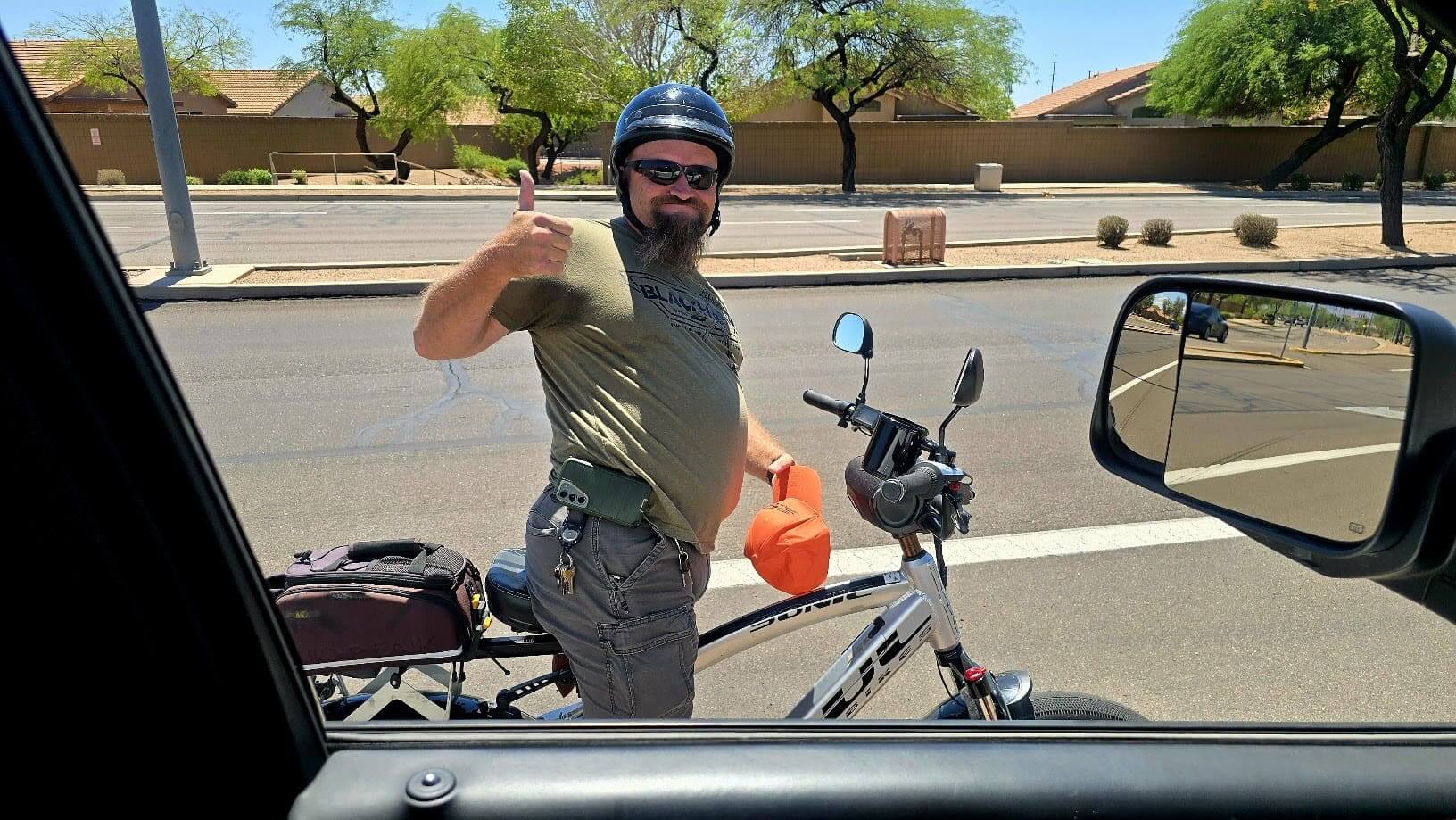Man on bike giving thumbs up roadside.