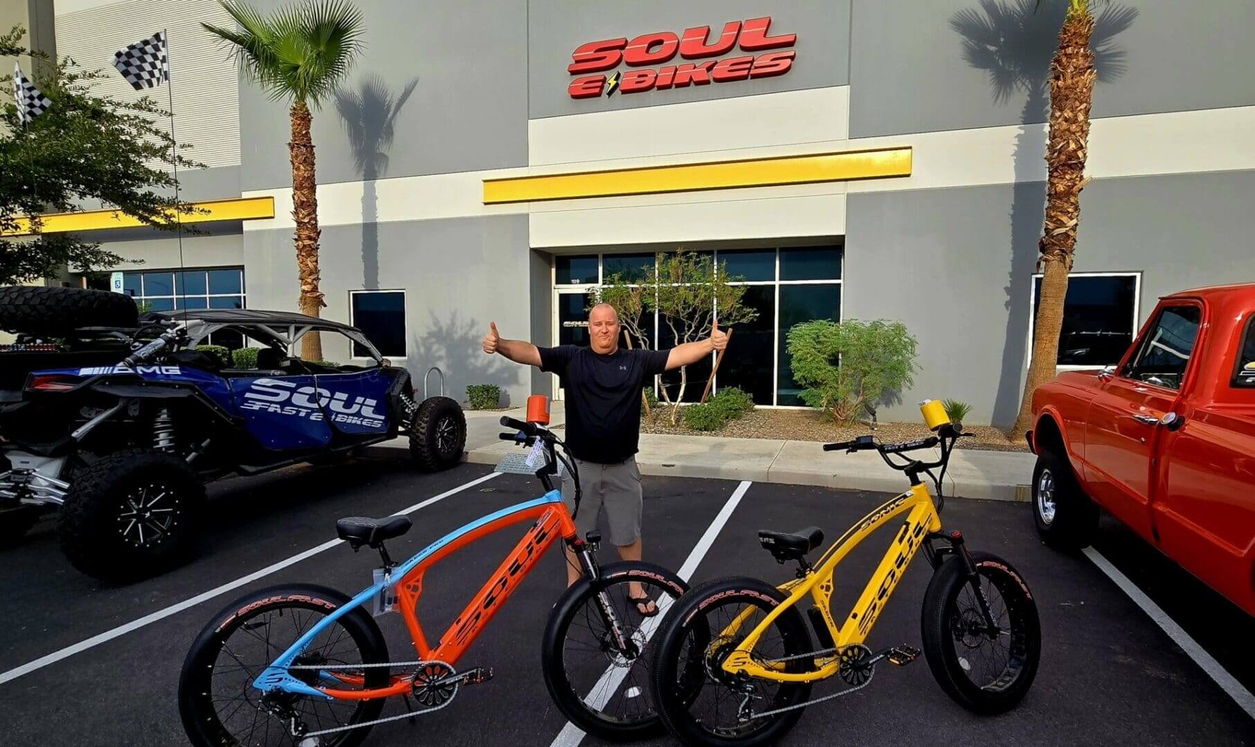 Man with two colorful bikes outside store.