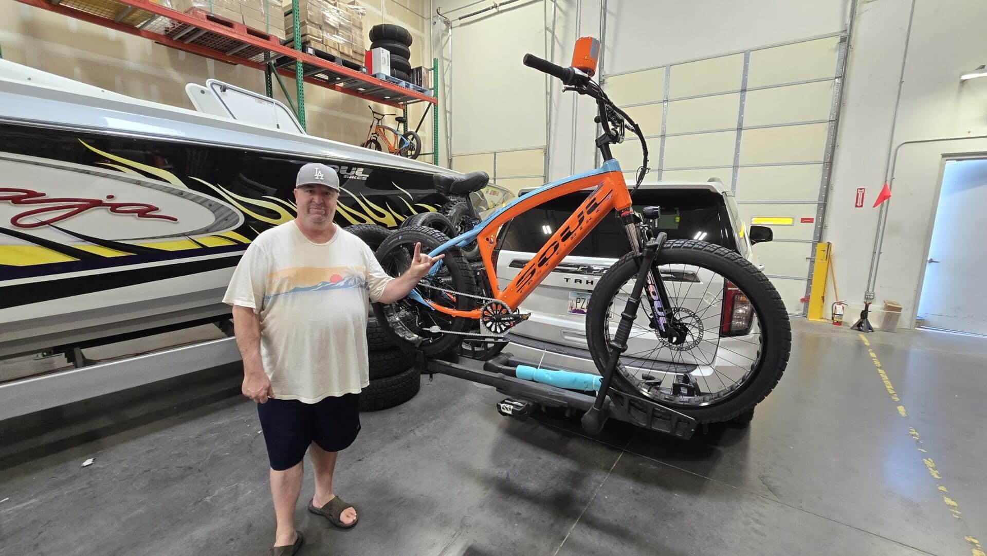 Man standing beside orange bicycle indoors.