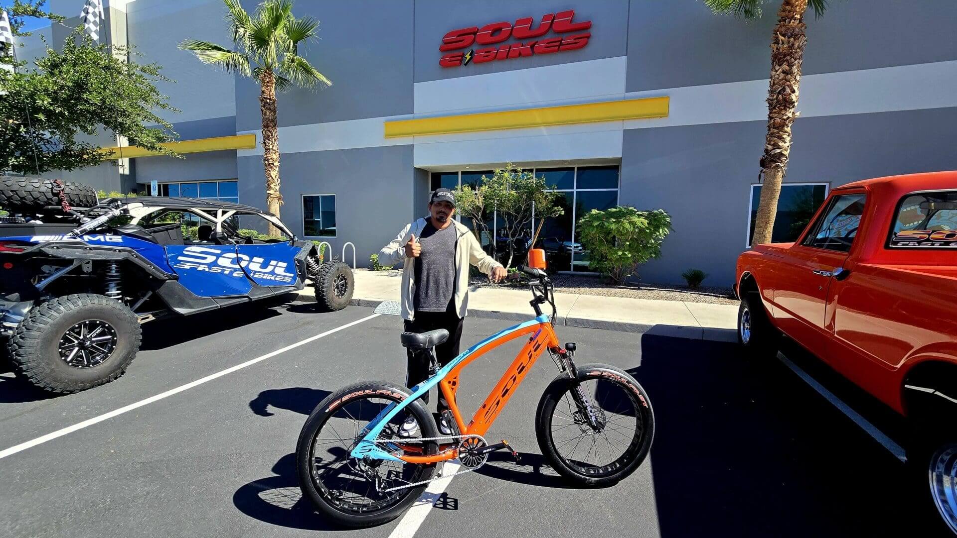 Person standing with an electric bike outside.