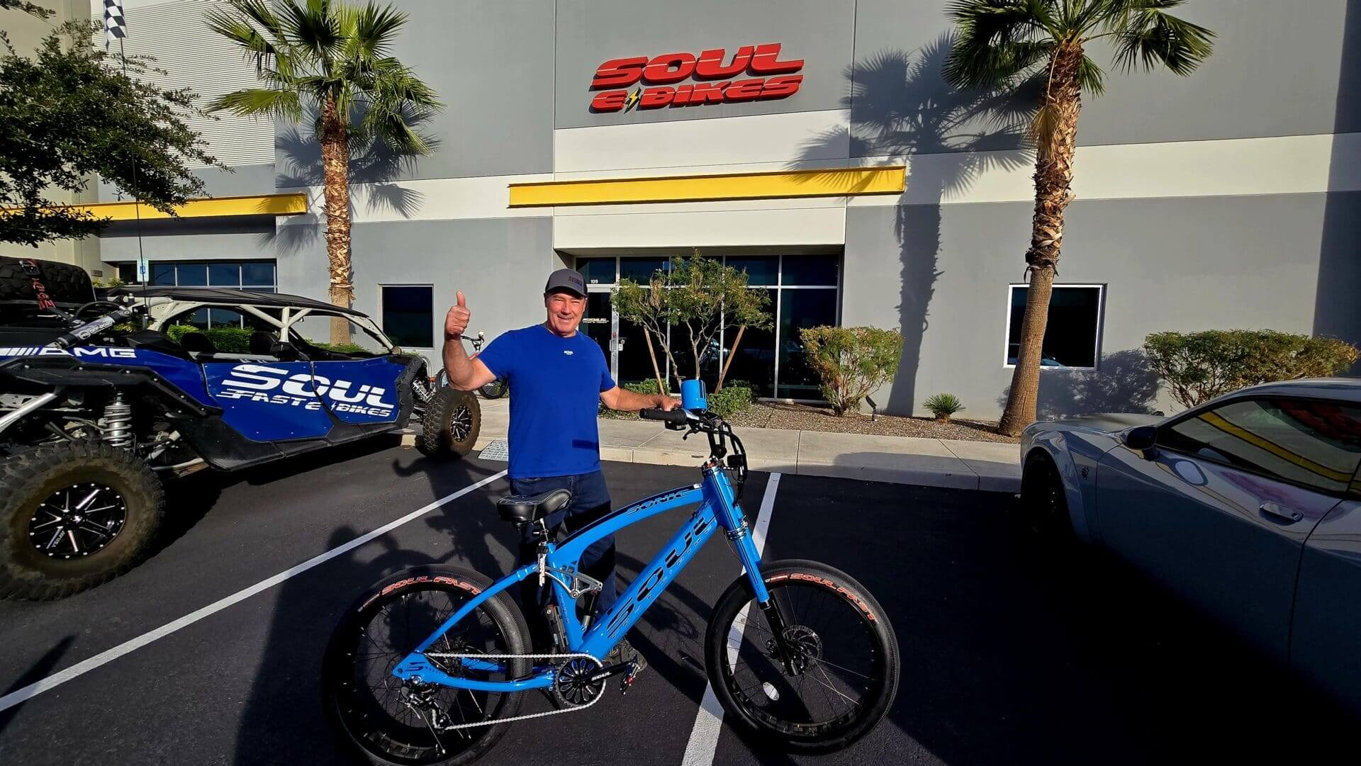 Man with bicycle outside Soul E Bikes store.