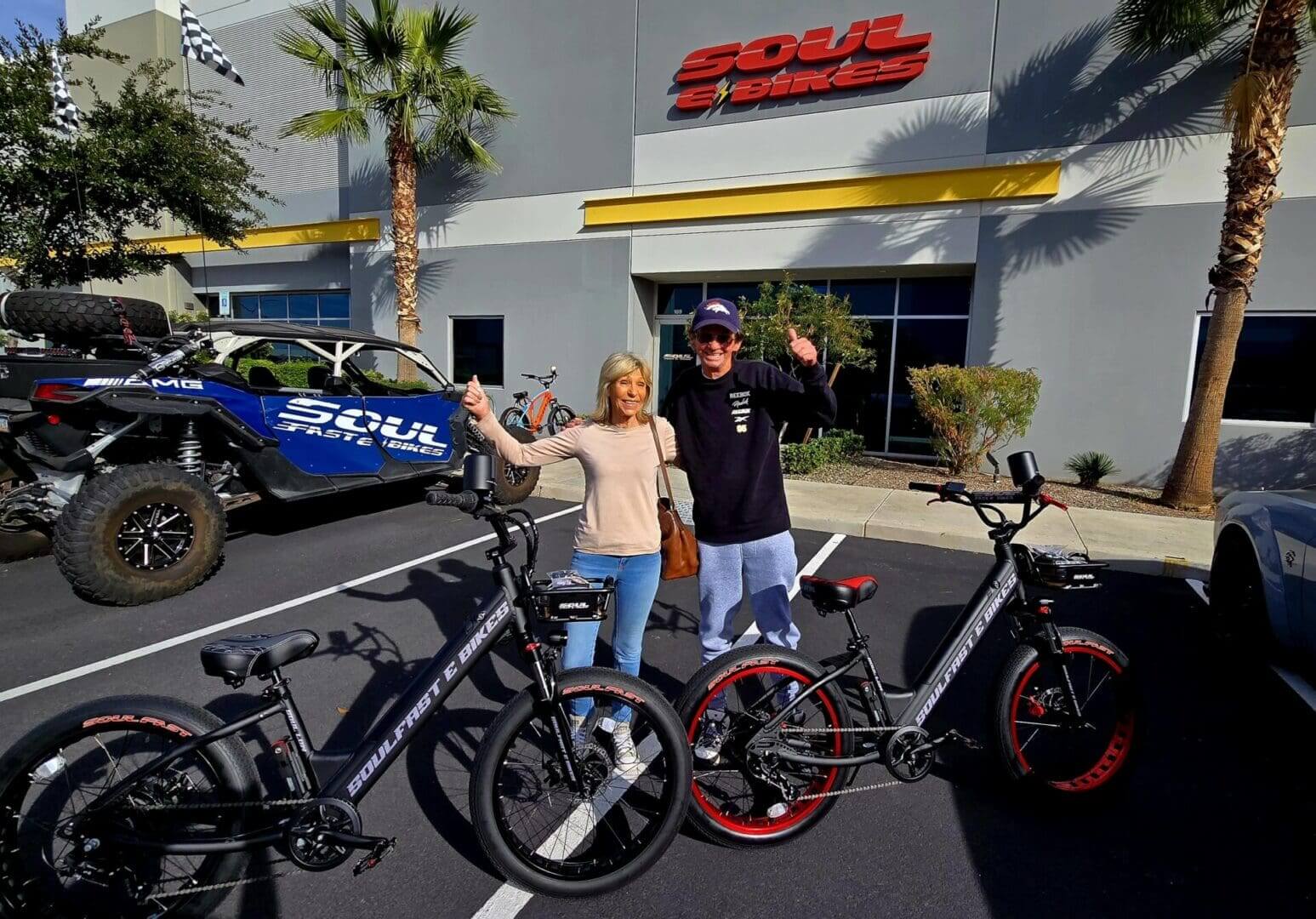 Two people with electric bikes, thumbs up.