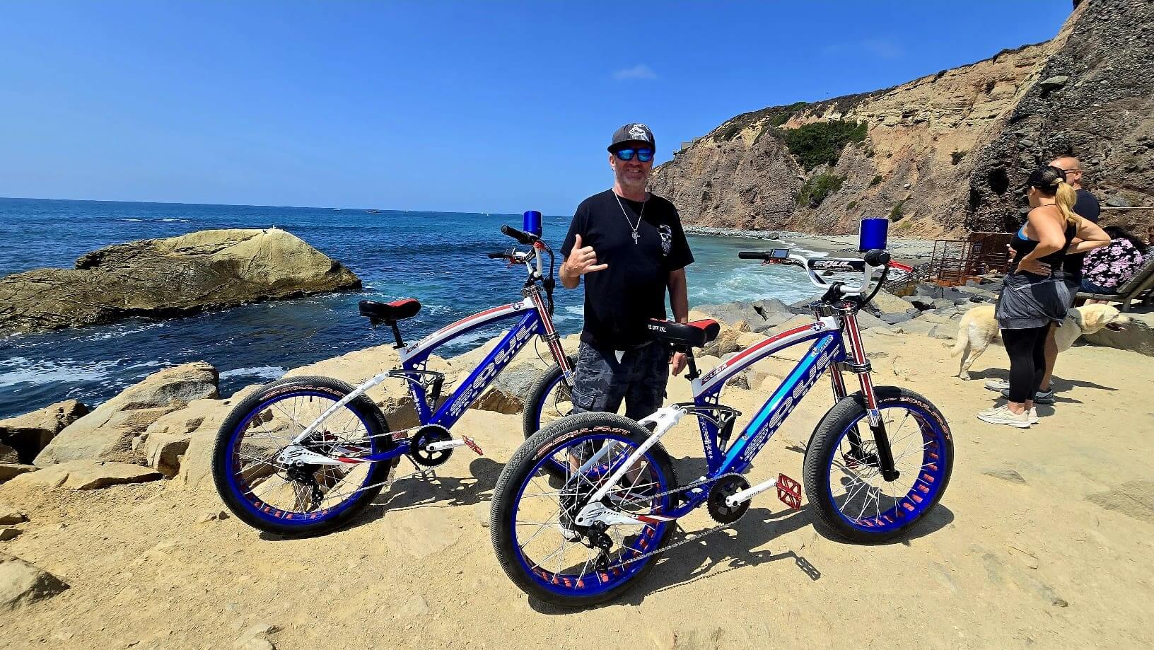Man with bikes on scenic coastal path.