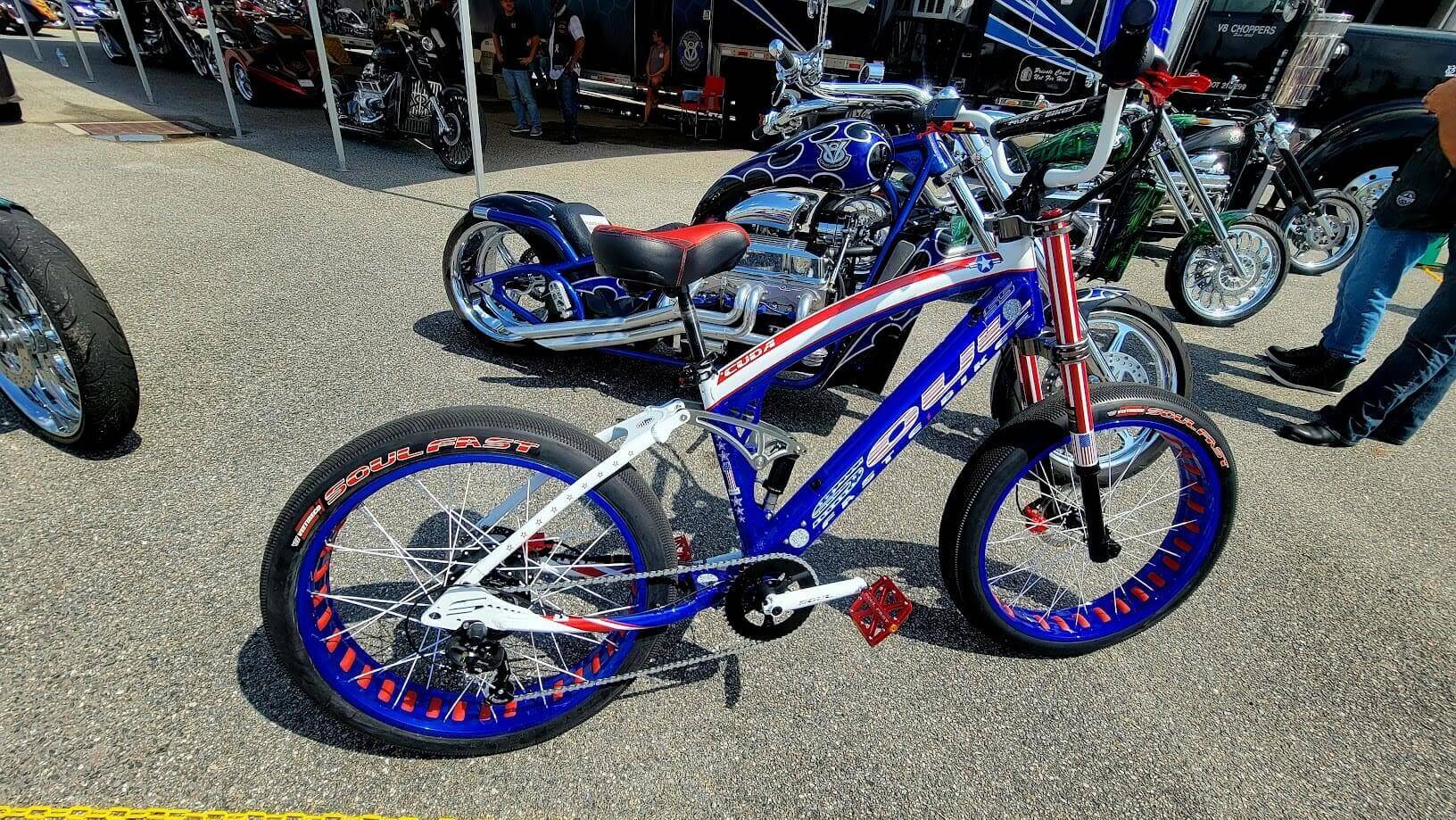 Custom motorbike and bicycle displayed outdoors.