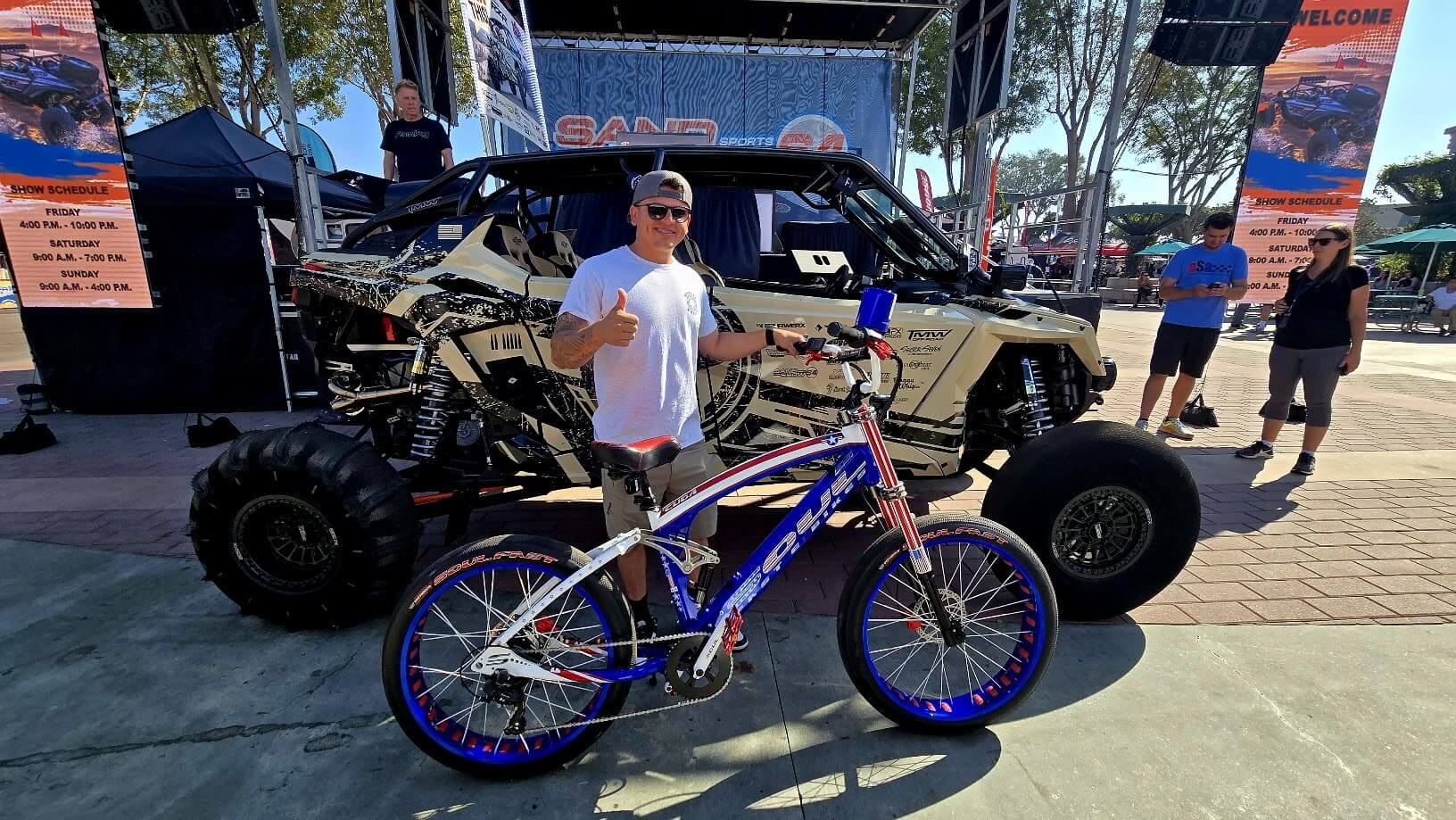 Man with bicycle in front of dune buggy.