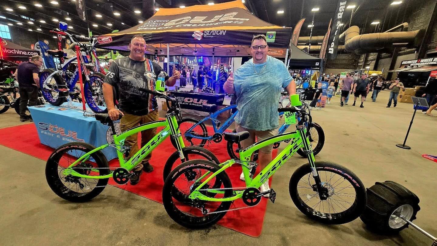 Two people with neon green bicycles indoors.