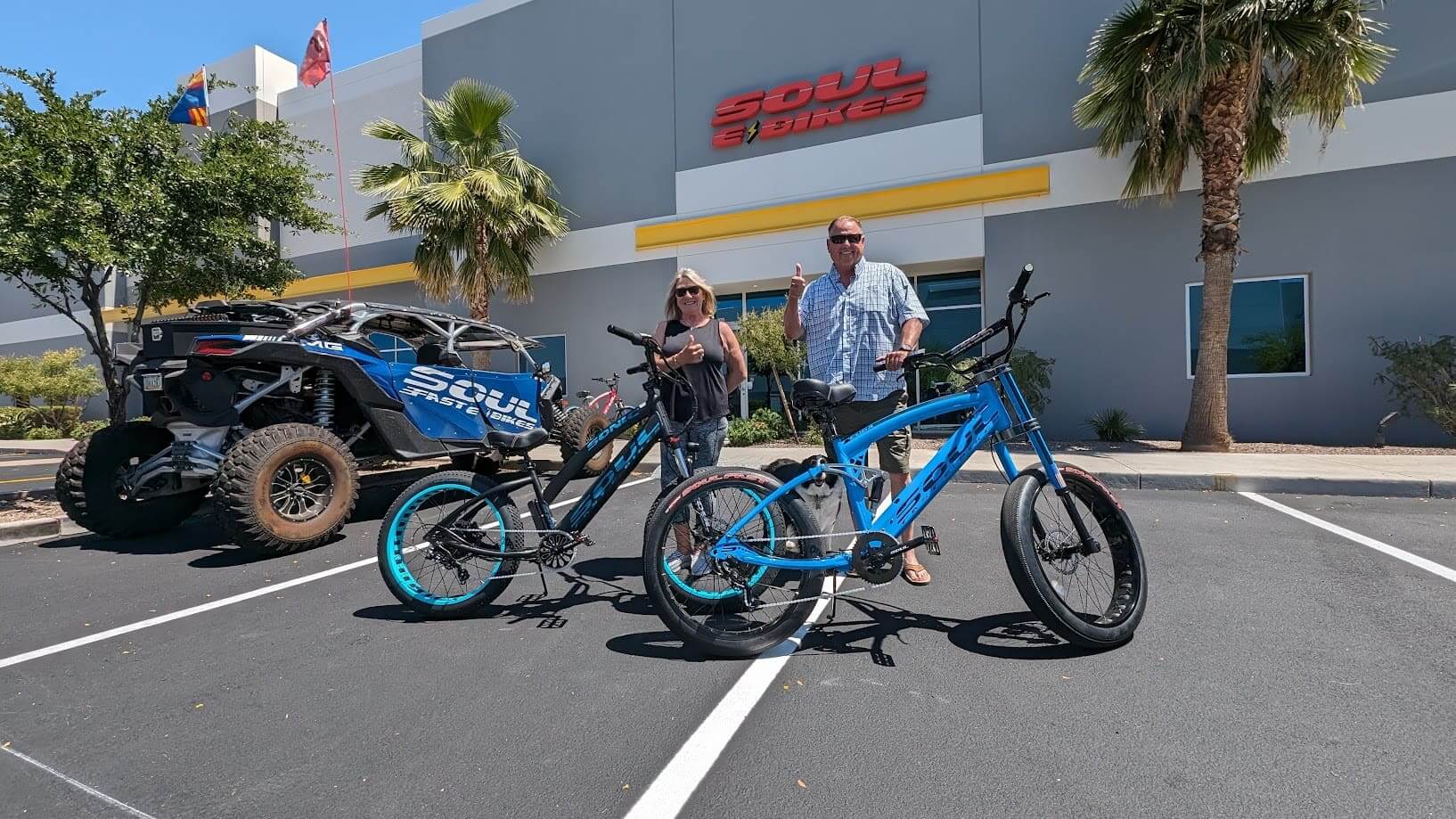 Two people with electric bikes outside showroom.