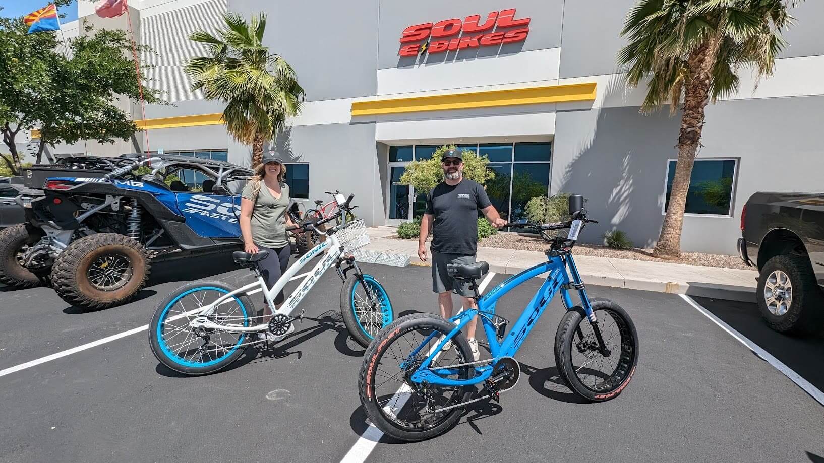 Two people with electric bikes outside store.