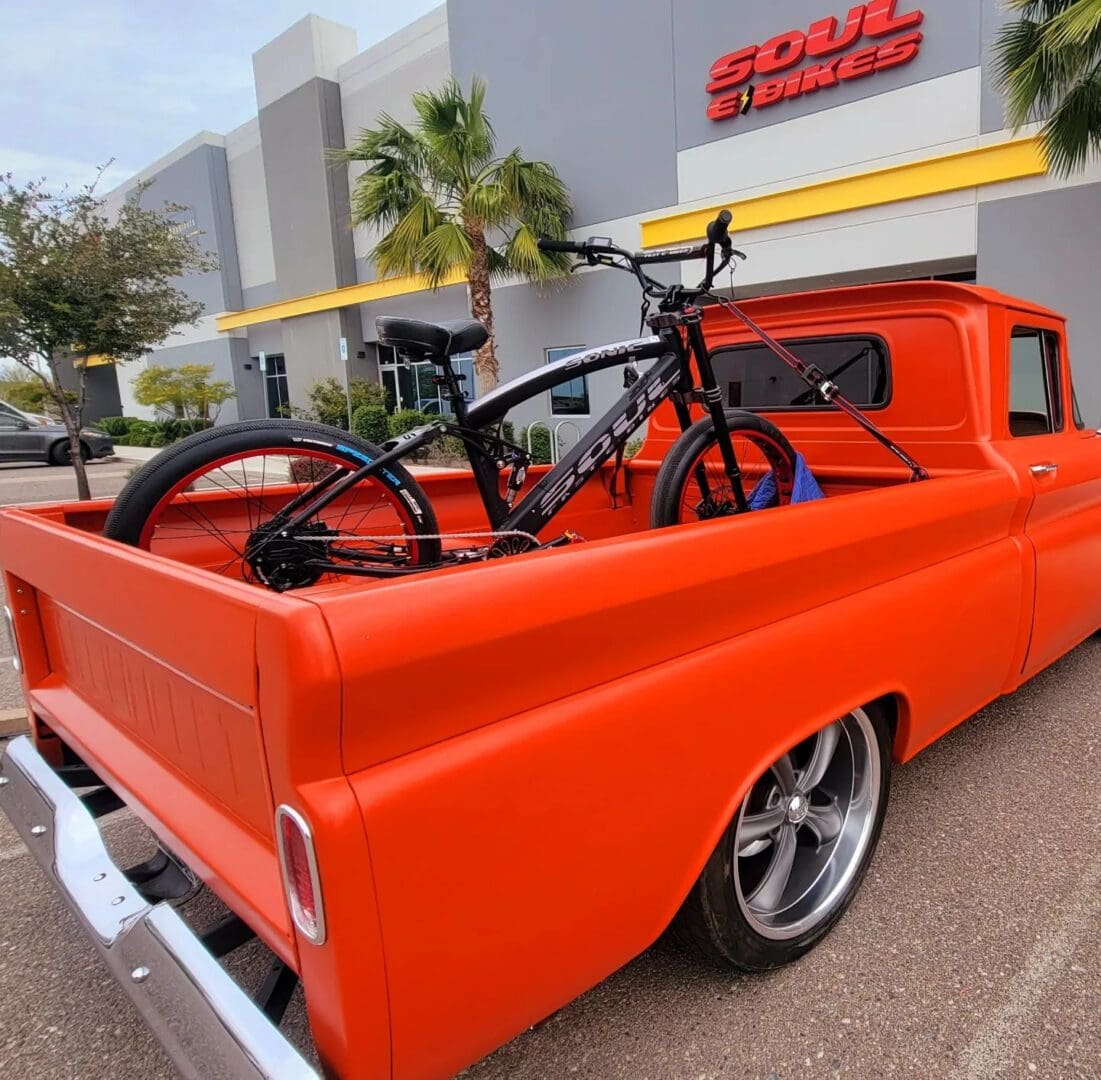 Orange truck with bike in the back.