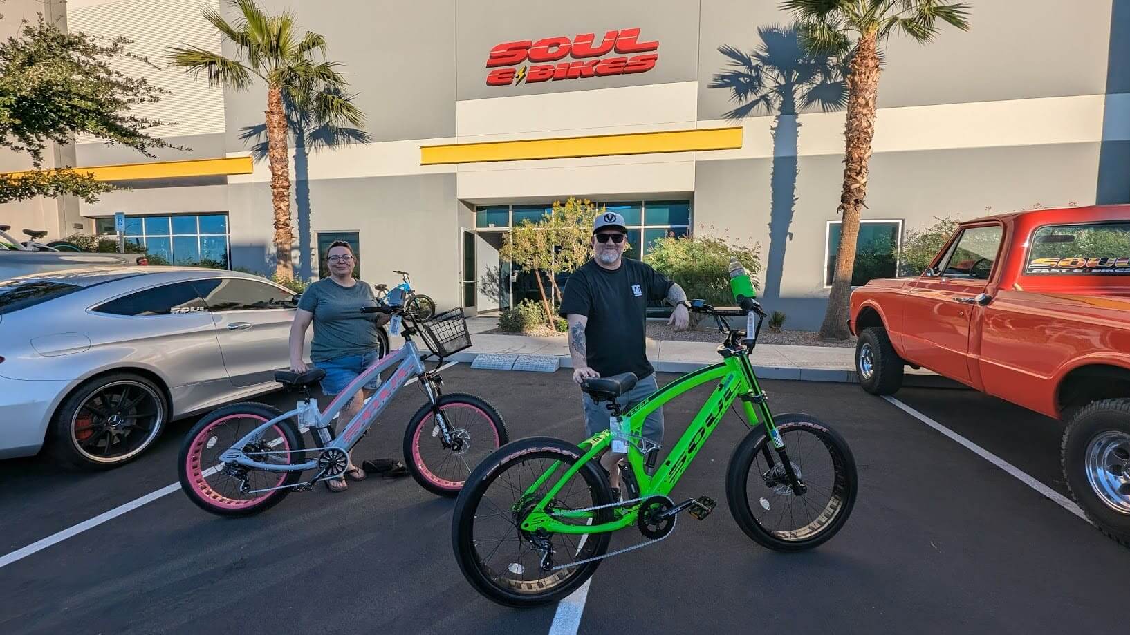 Two people with electric bikes outside store.