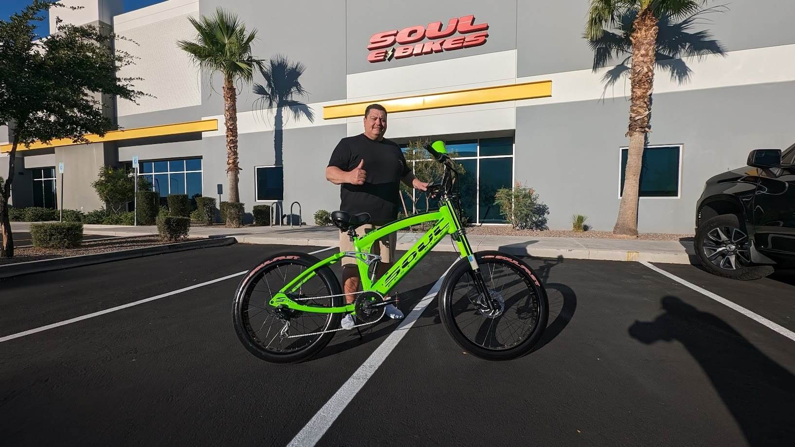Man with green bike outside Soul eBikes store.
