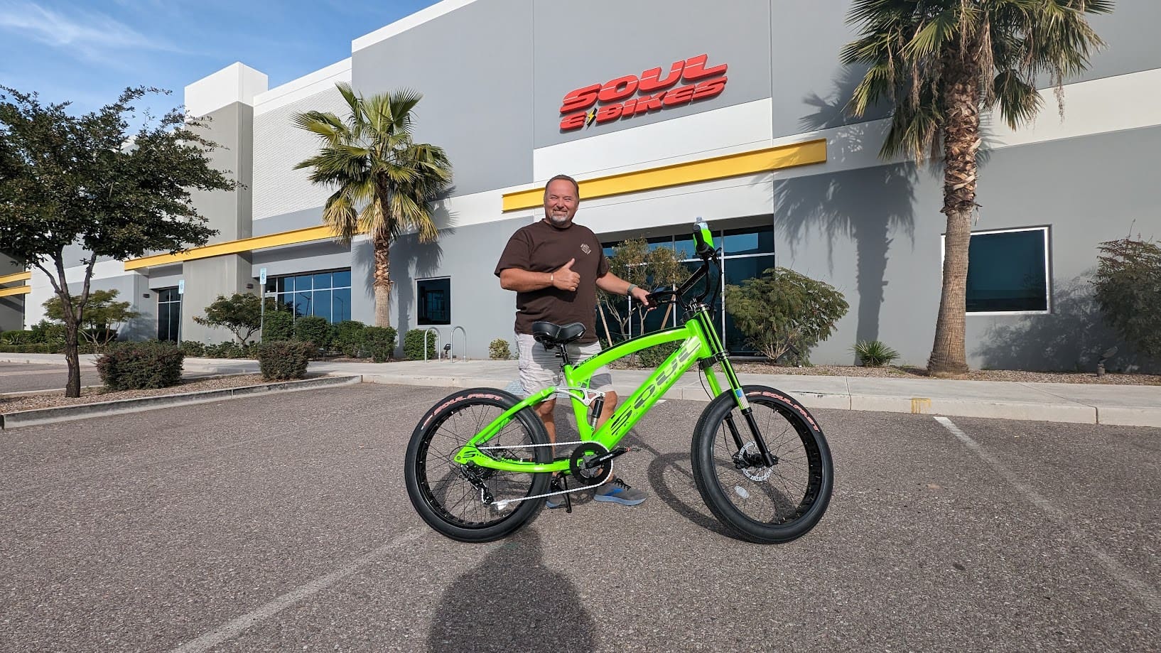 Man standing with bright green bicycle outdoors.