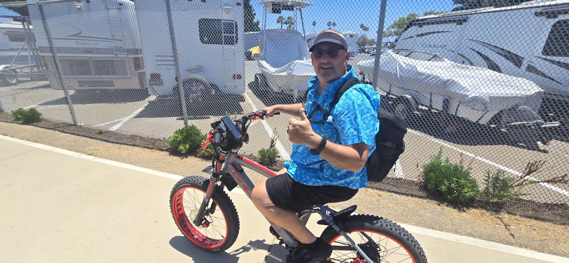 Man on bike giving thumbs up, smiling.