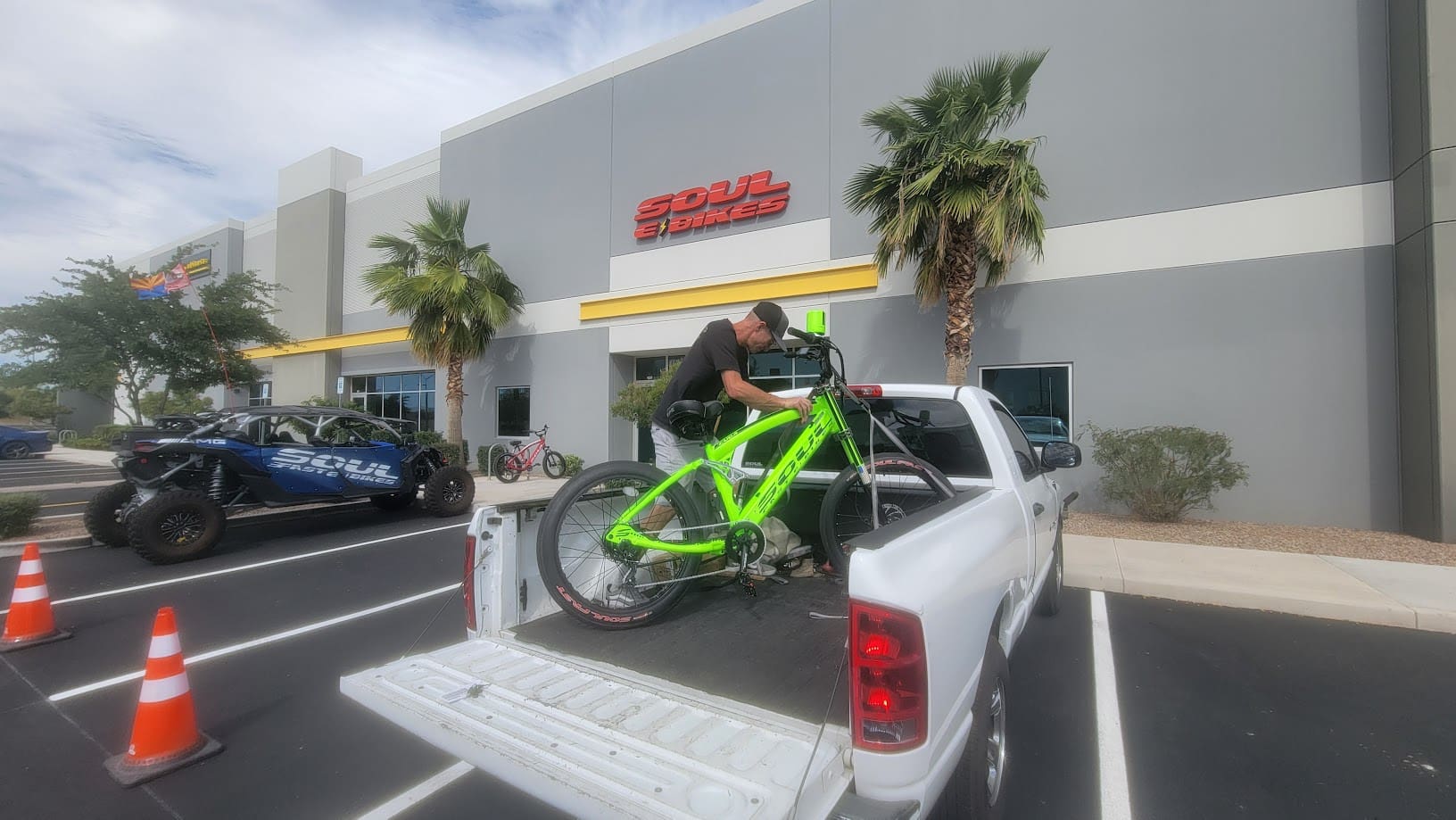 Man loading green bike onto pickup truck.