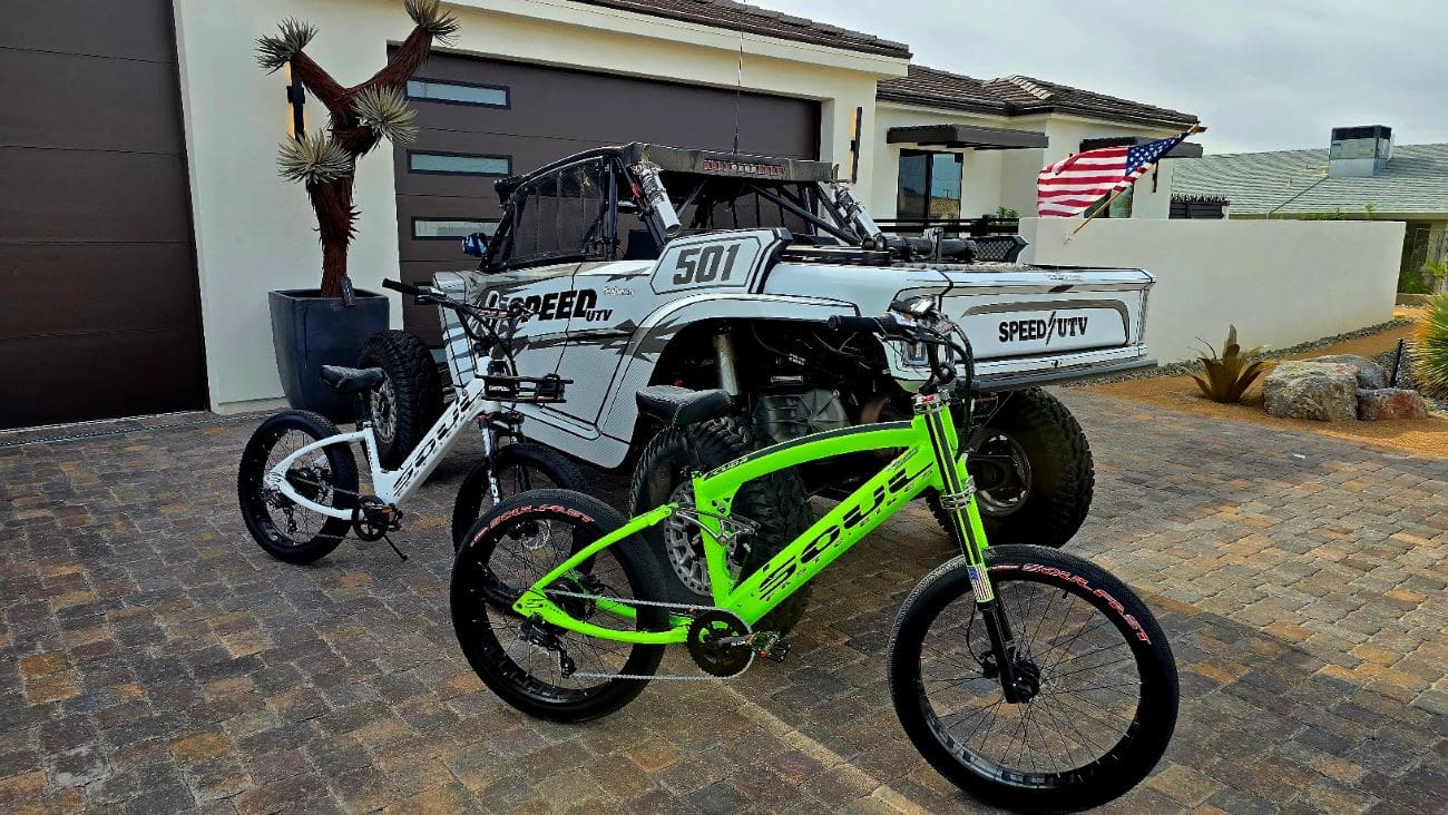 Two bicycles parked beside an off-road vehicle.