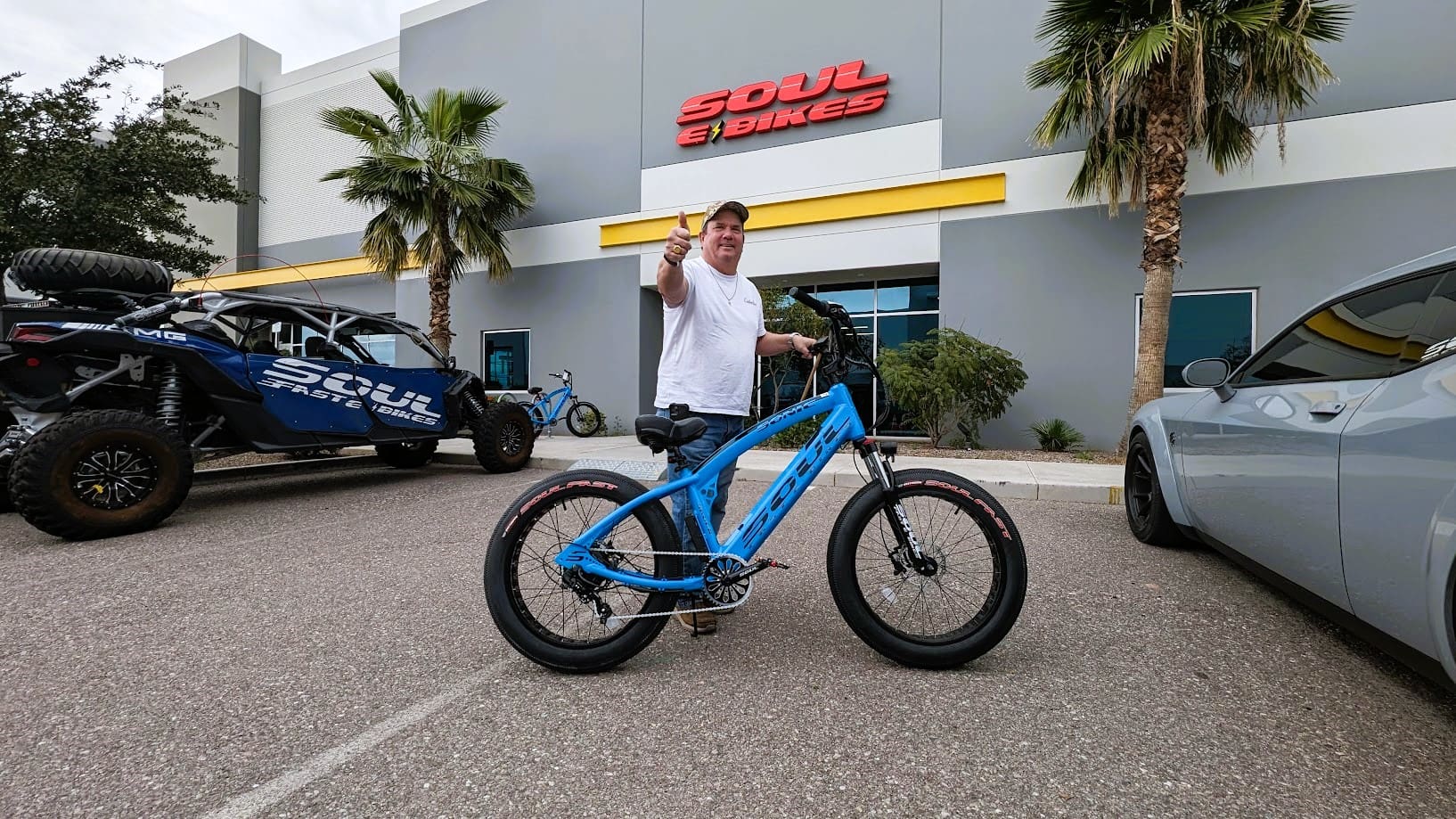 Man standing with a blue bike outside.