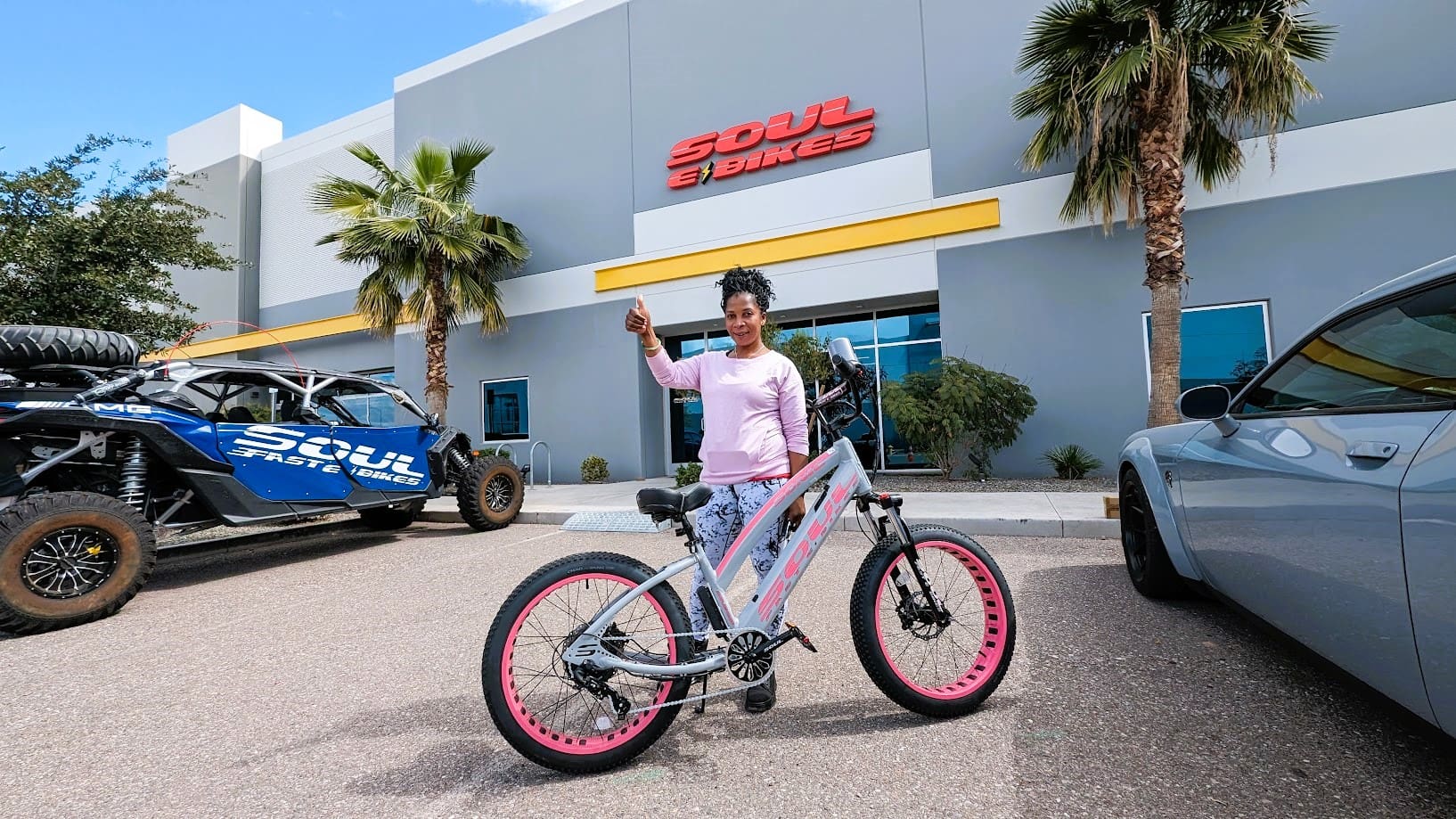 Woman holding keys beside bicycle, smiling outside.