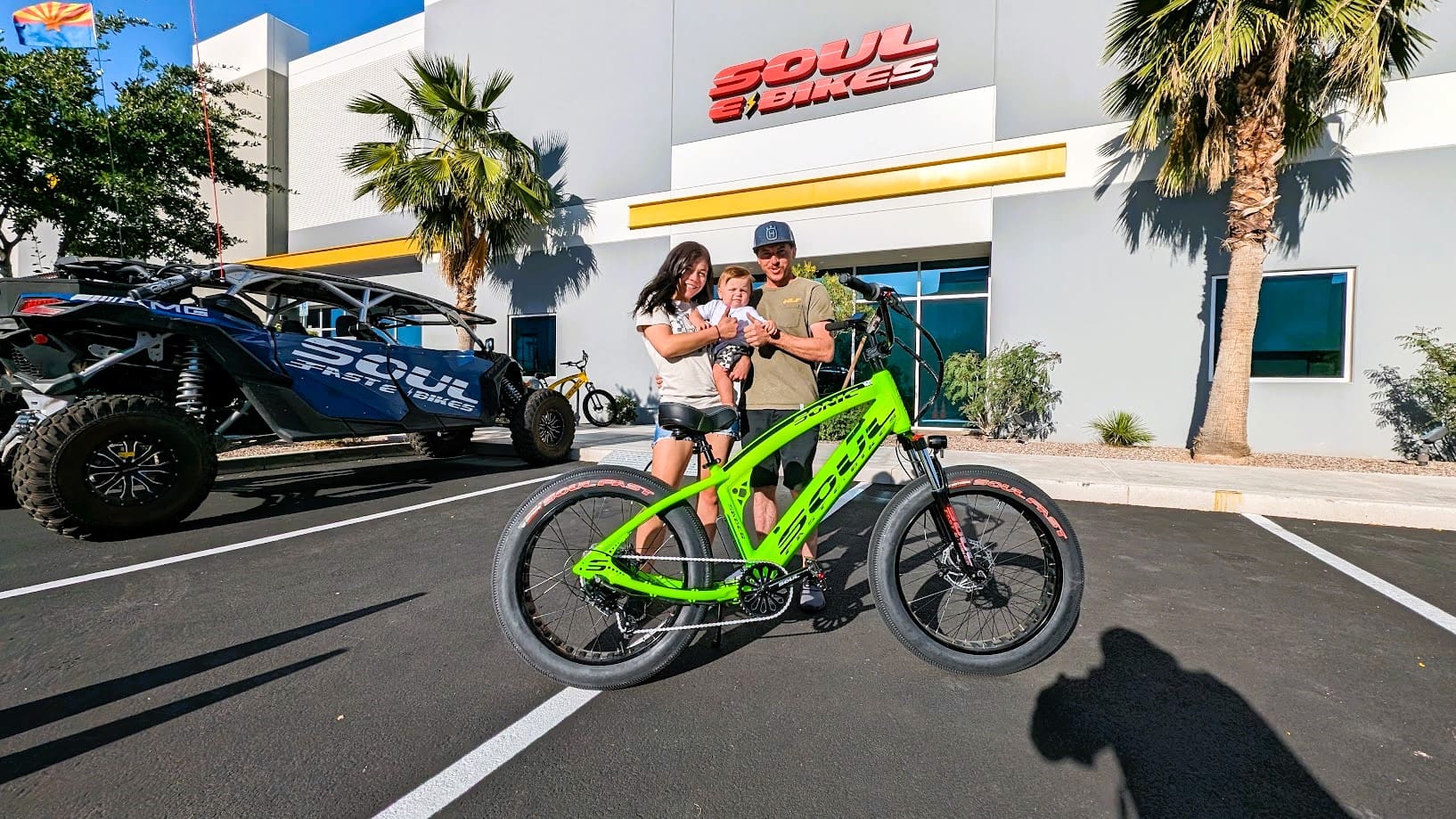 People posing with green electric bike outside.