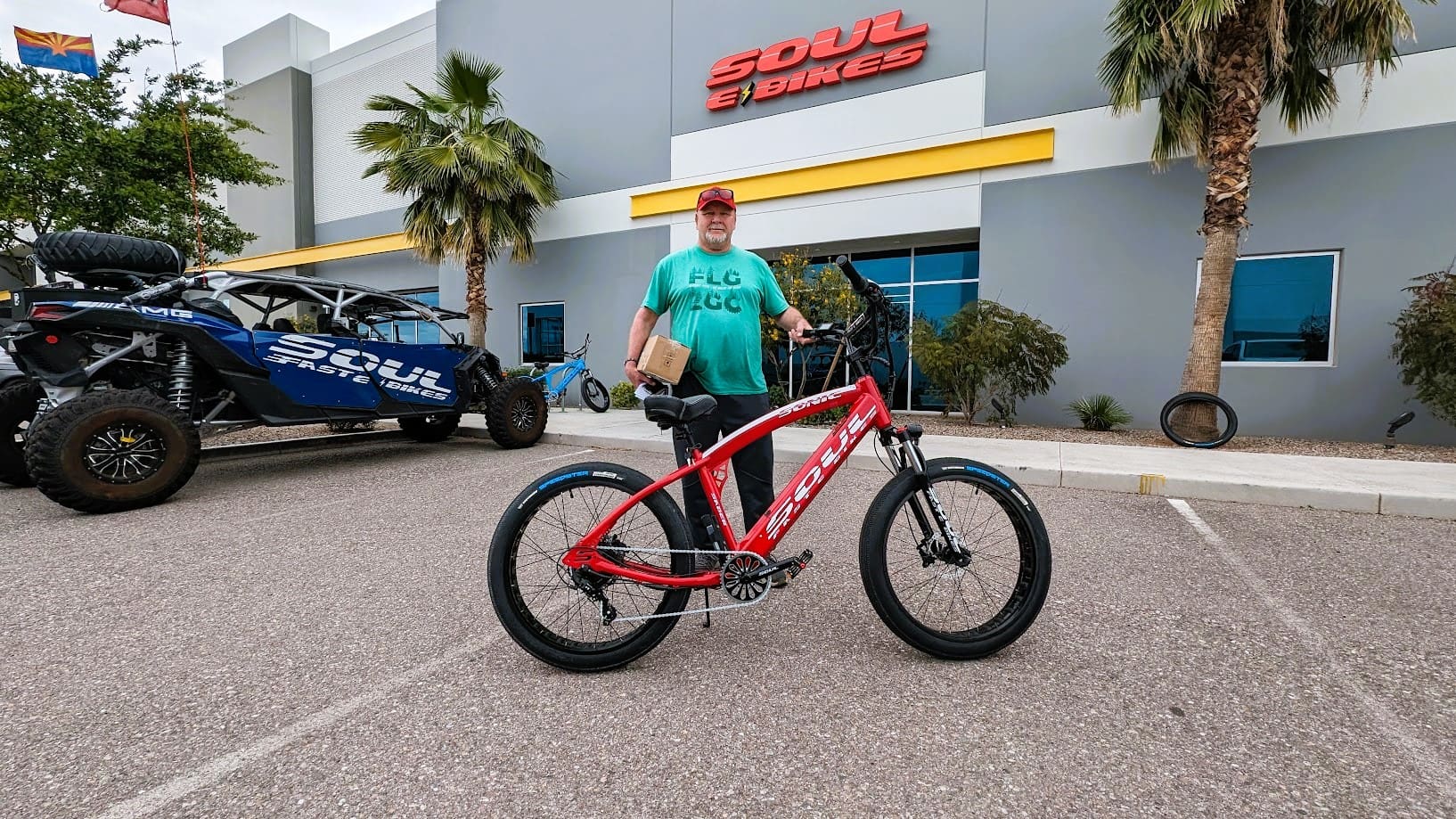 Man with red bicycle outside Soul Cycles shop.