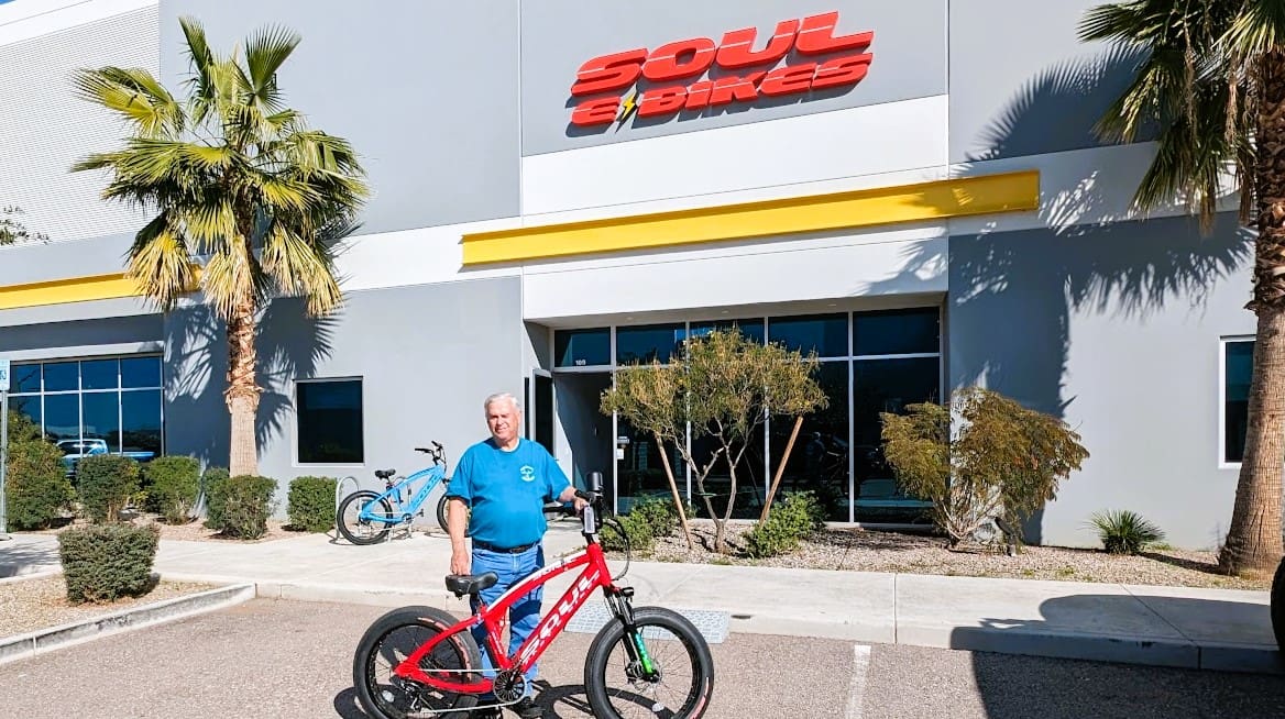 Man with bicycle outside Soul Bikes building.