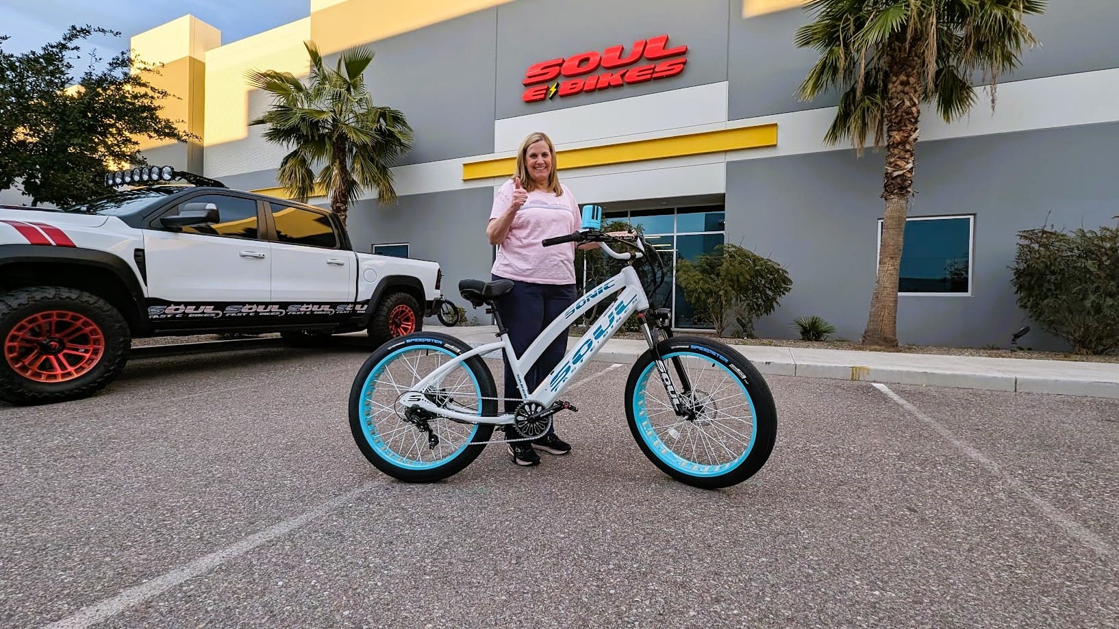 Woman standing with a bike outside store.