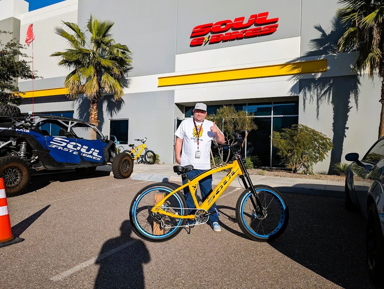 Man posing with yellow bike outside store.