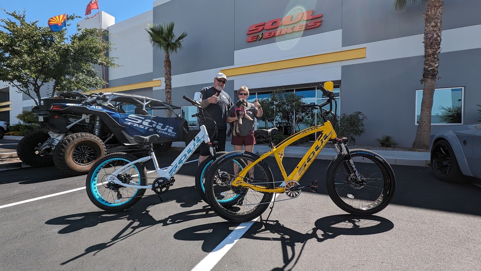 Two people standing with electric bikes outside.
