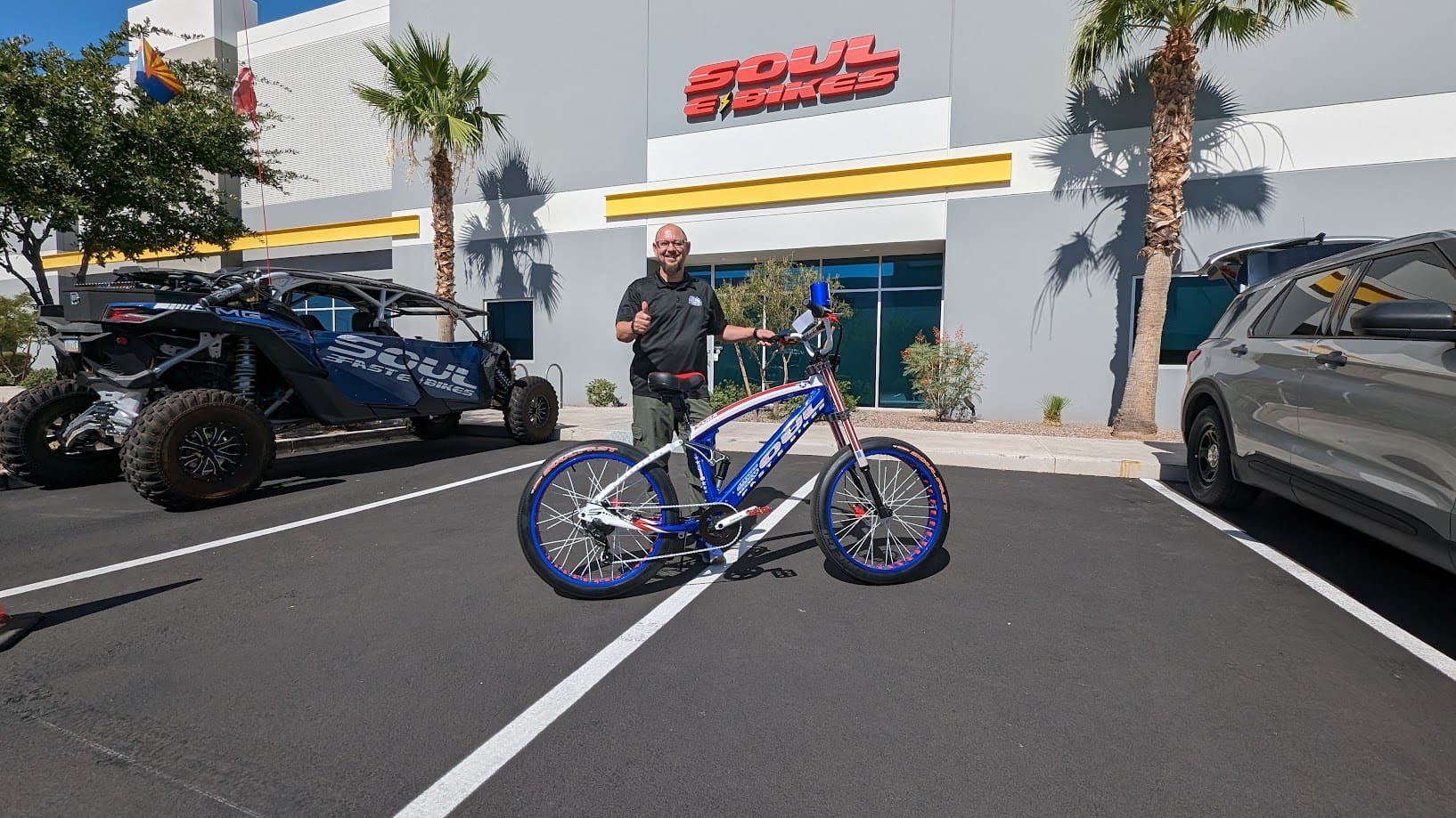 Man standing with bike in parking lot.