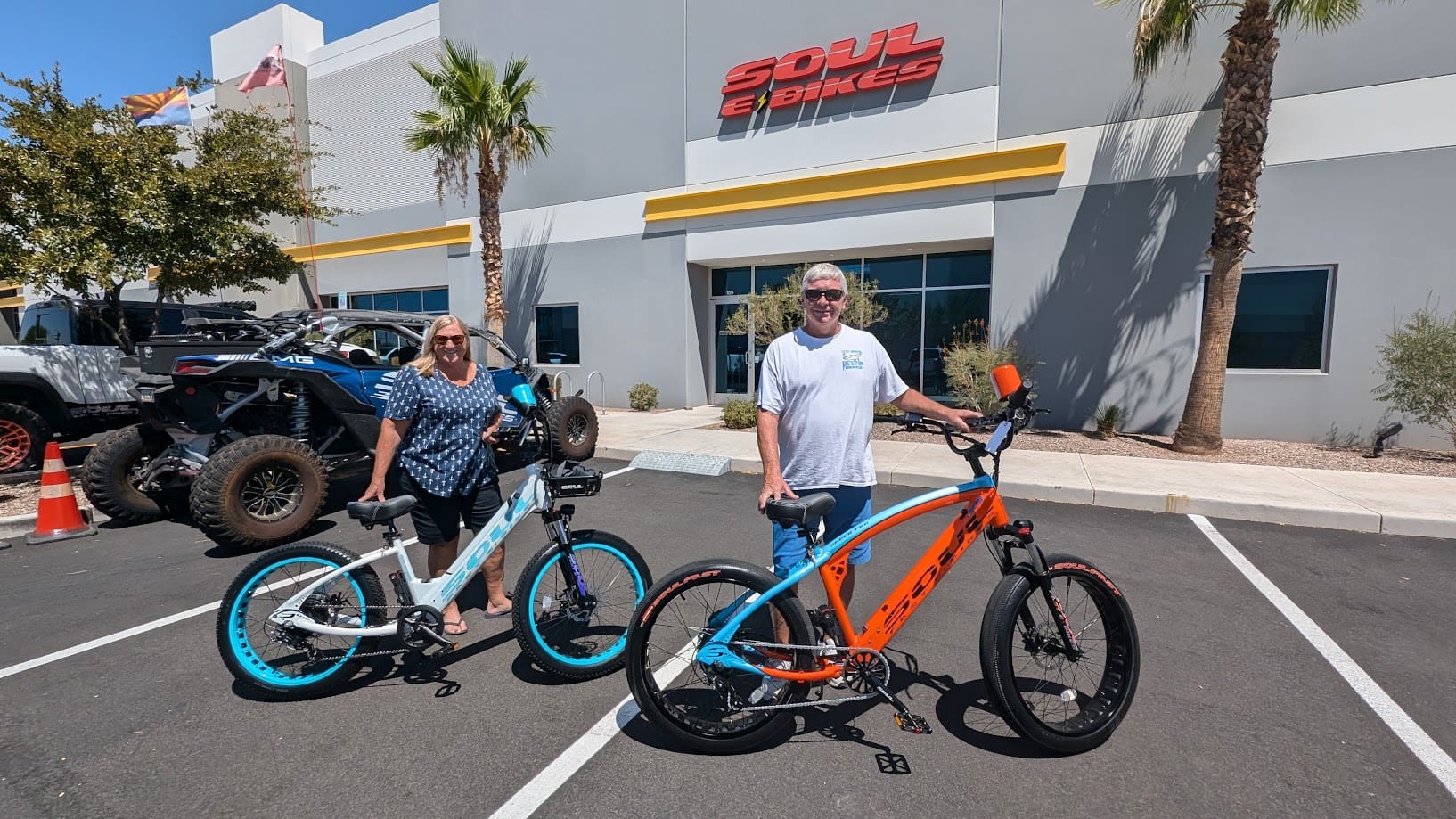 Two people with electric bikes outside store.